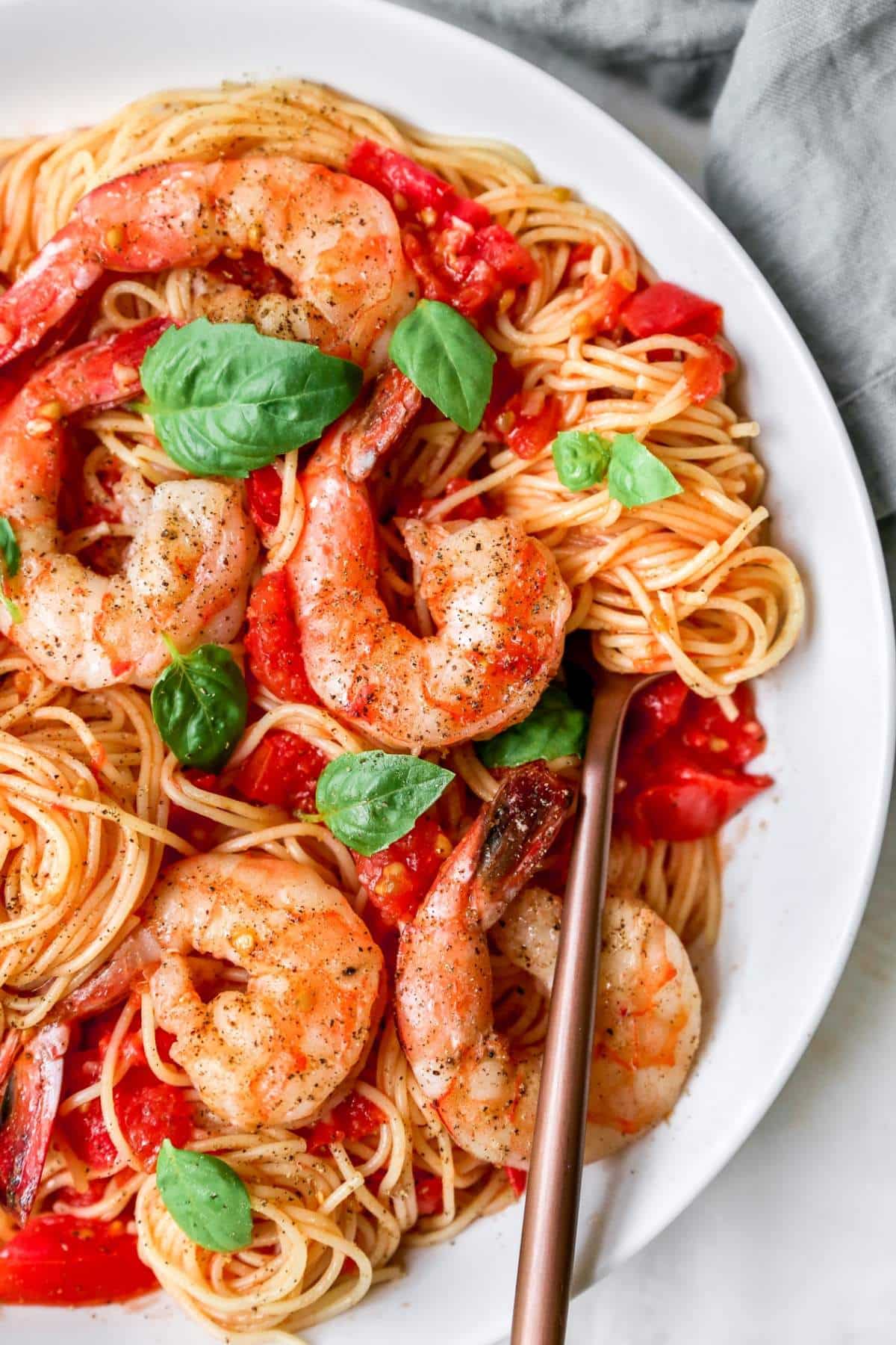 Pasta Pomodoro topped with shrimp and basil and swirled around a fork.