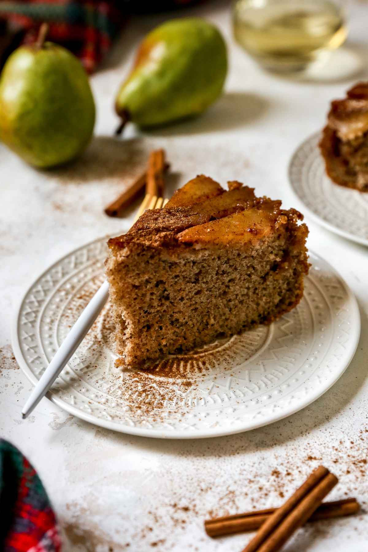 Slice of spice cake topped with pear slices, cinnamon and brown sugar.
