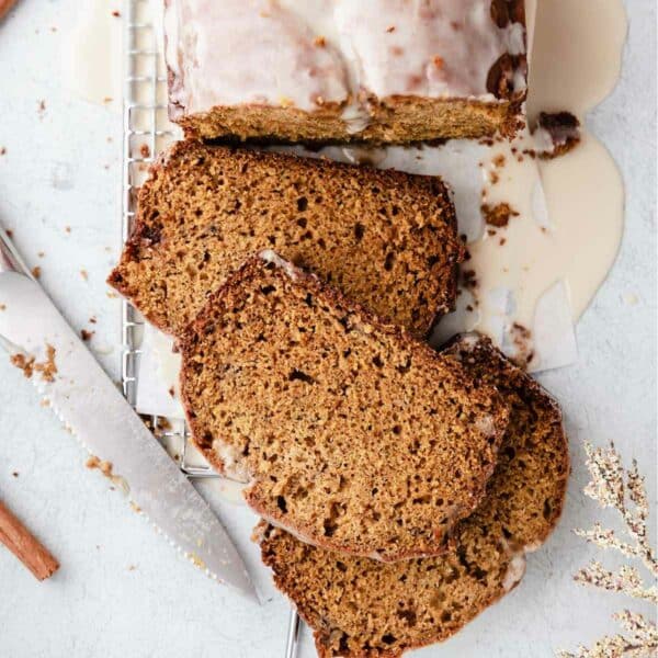 Pumpkin banana bread cut into slices and topped with a glaze.