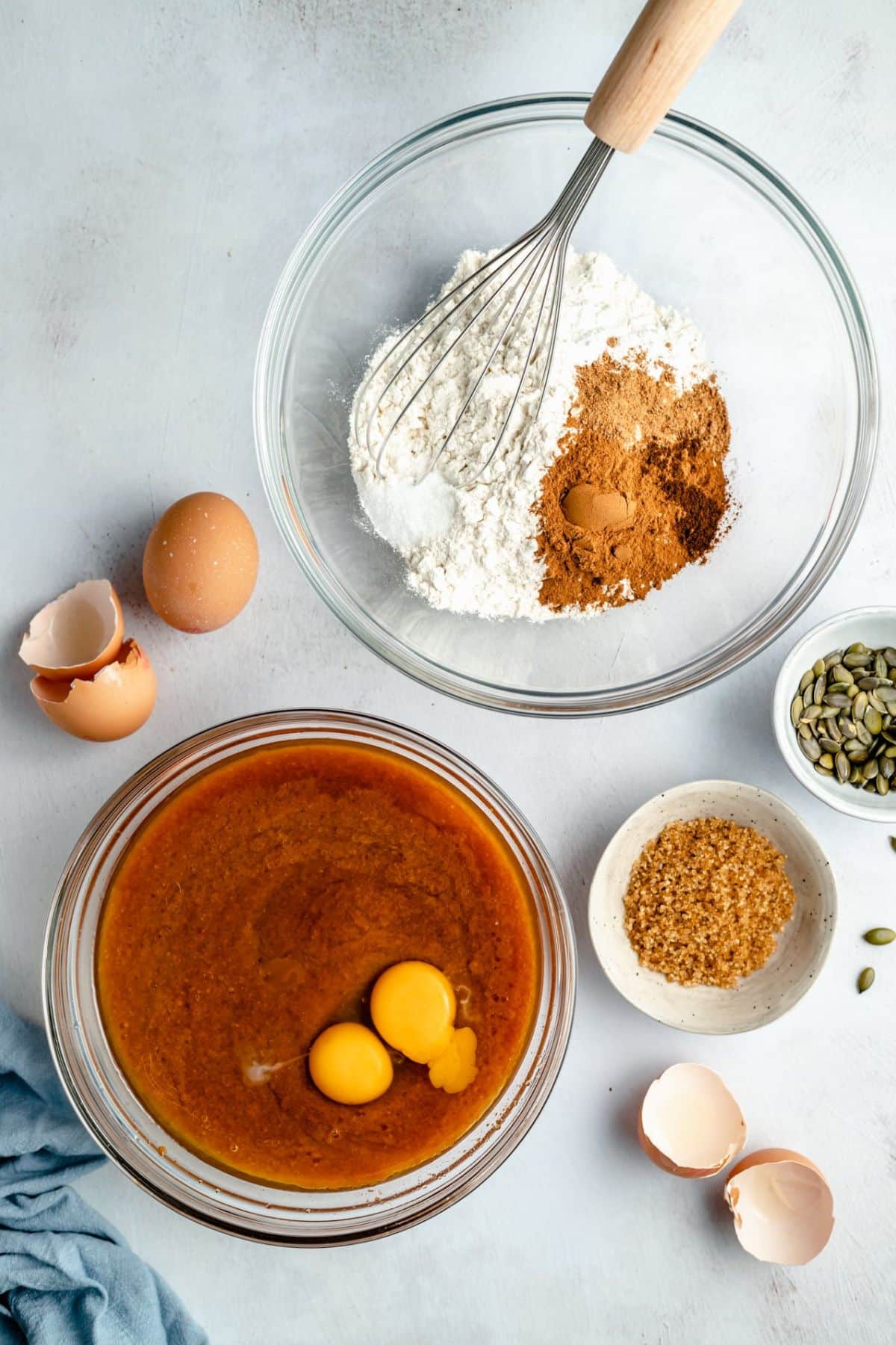 Mixing flour with spices in one bowl and eggs with oil and pumpkin in another bowl.