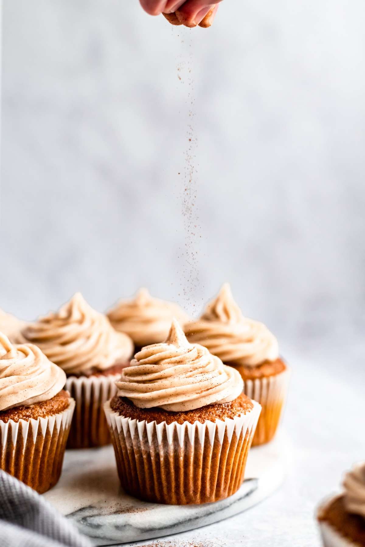 Sprinkling cinnamon over the top of frosted cupcakes.