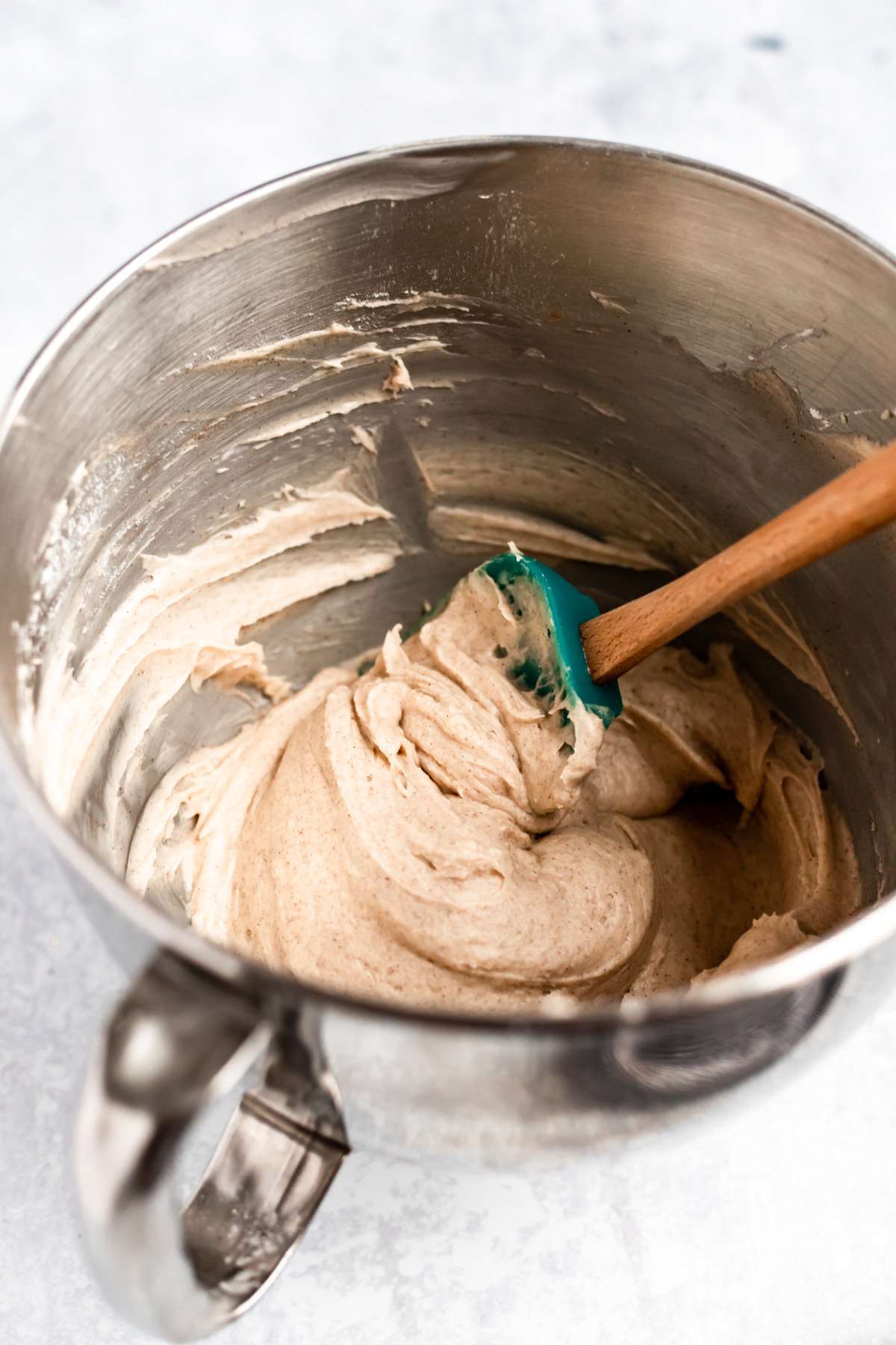 Stirring together cinnamon cream cheese frosting in a large mixing bowl.