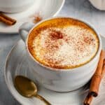 Mug of coffee made topped with foamy cream and spices.