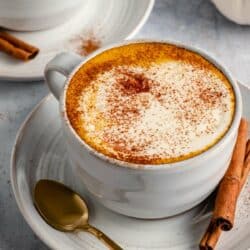 Mug of coffee made topped with foamy cream and spices.