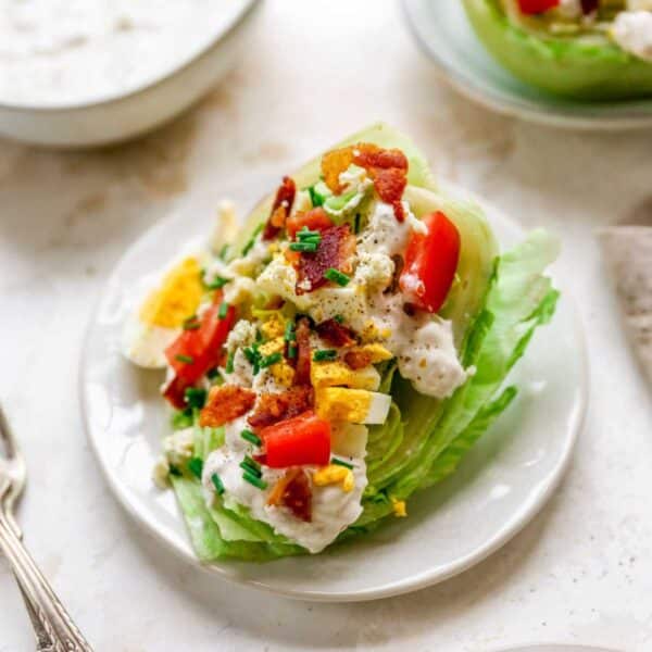 Wedge salad topped with blue cheese, bacon, tomatoes and hard-boiled eggs.