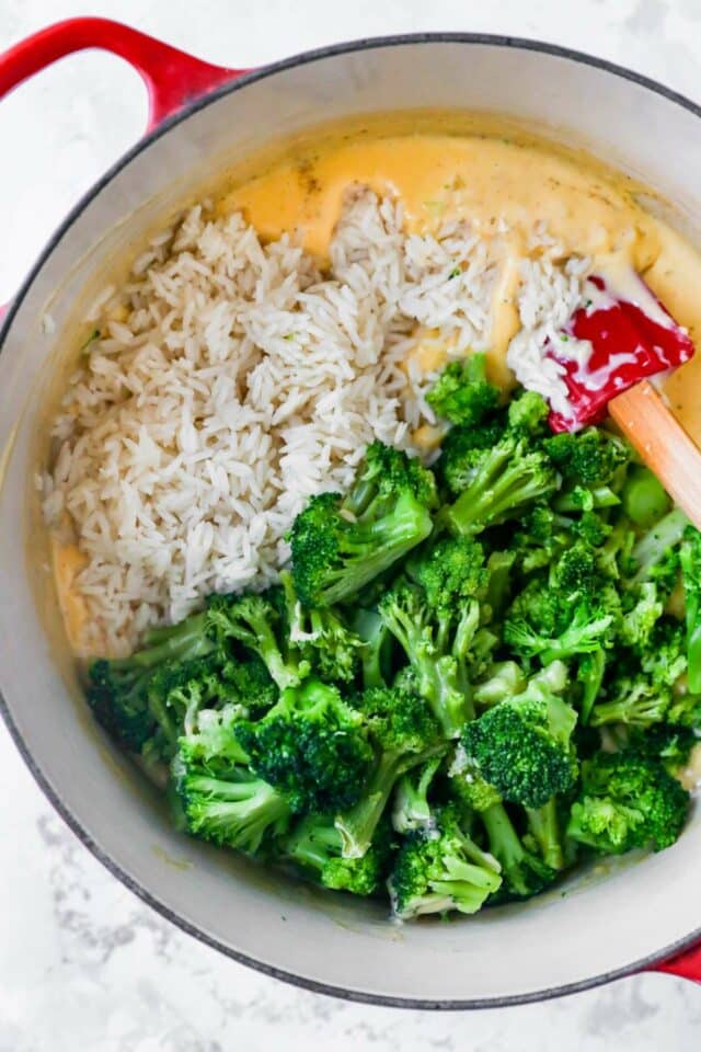 Stirring rice and broccoli with cheese sauce.