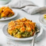 Serving of broccoli rice casserole on a small white plate with a fork.
