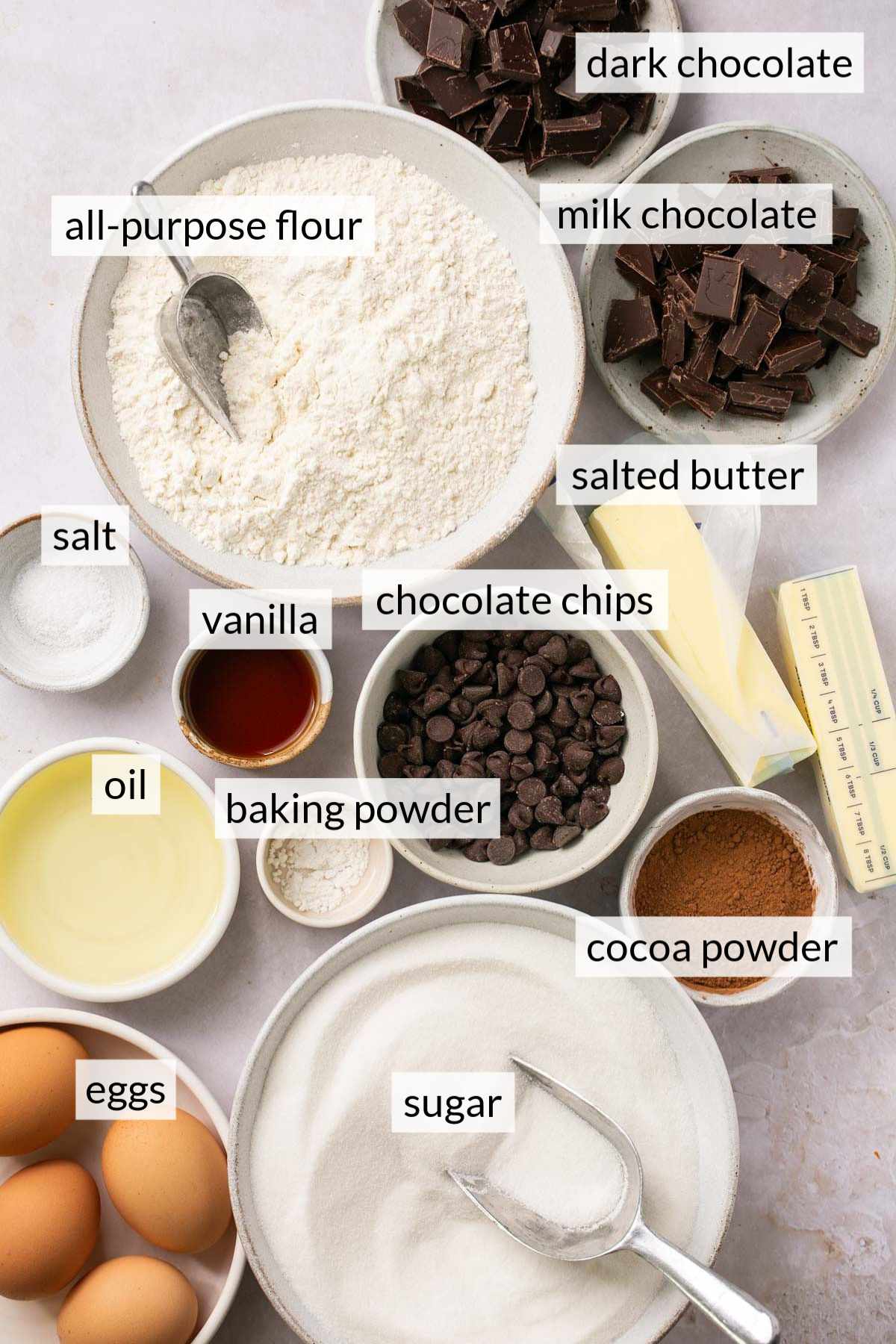 Small bowls with flour, sugar, eggs, chocolate and vanilla.