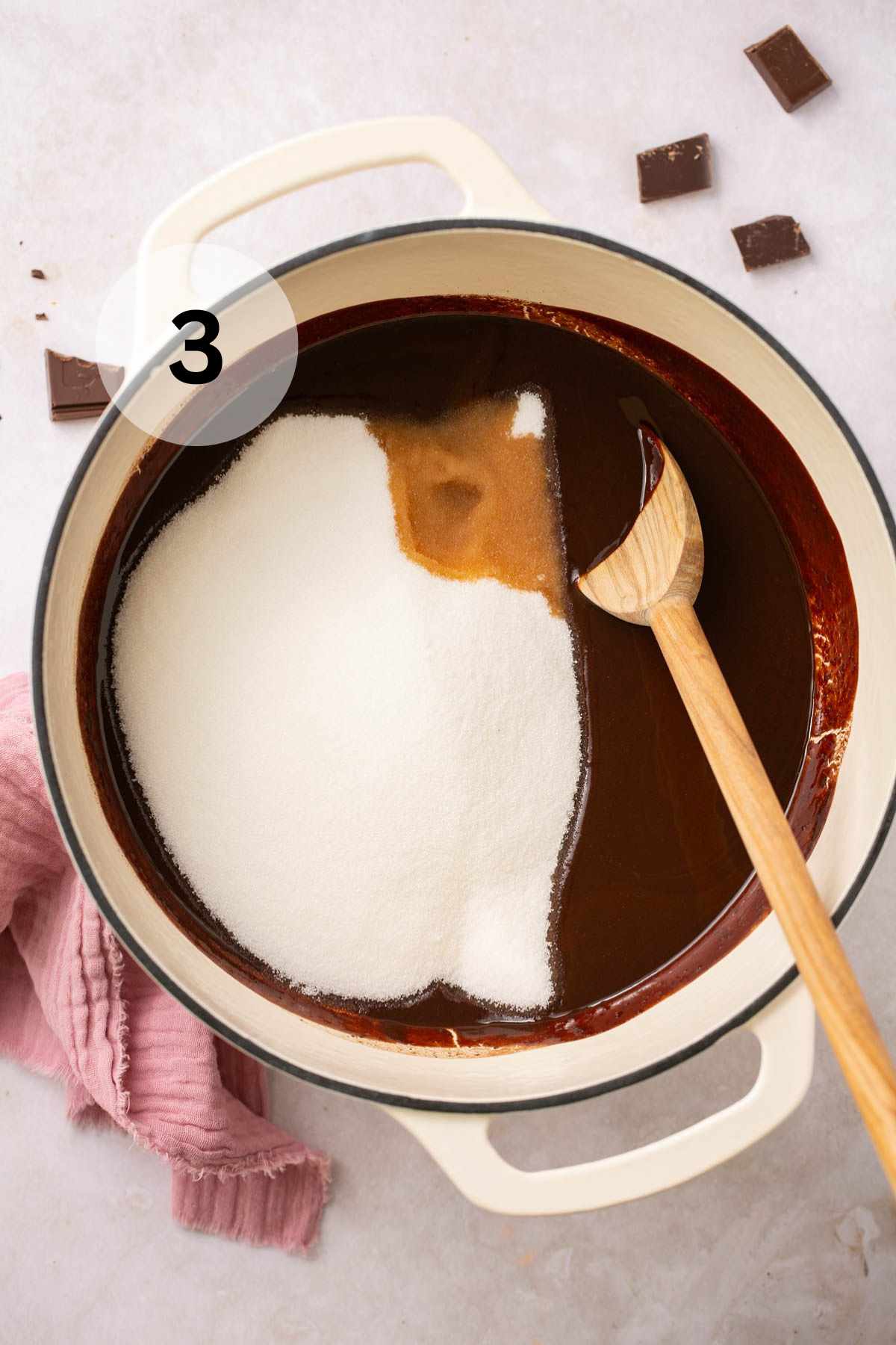 Using a wooden spoon to stir sugar and vanilla into melted chocolate.