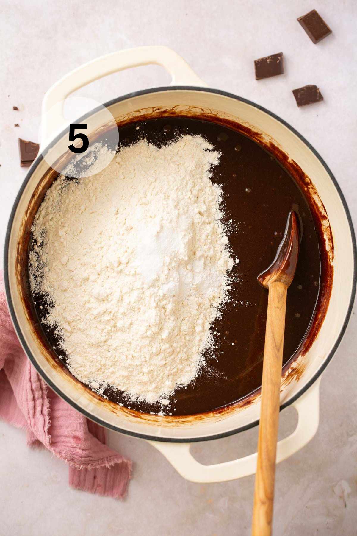 Adding flour to chocolate mixture in a pot.