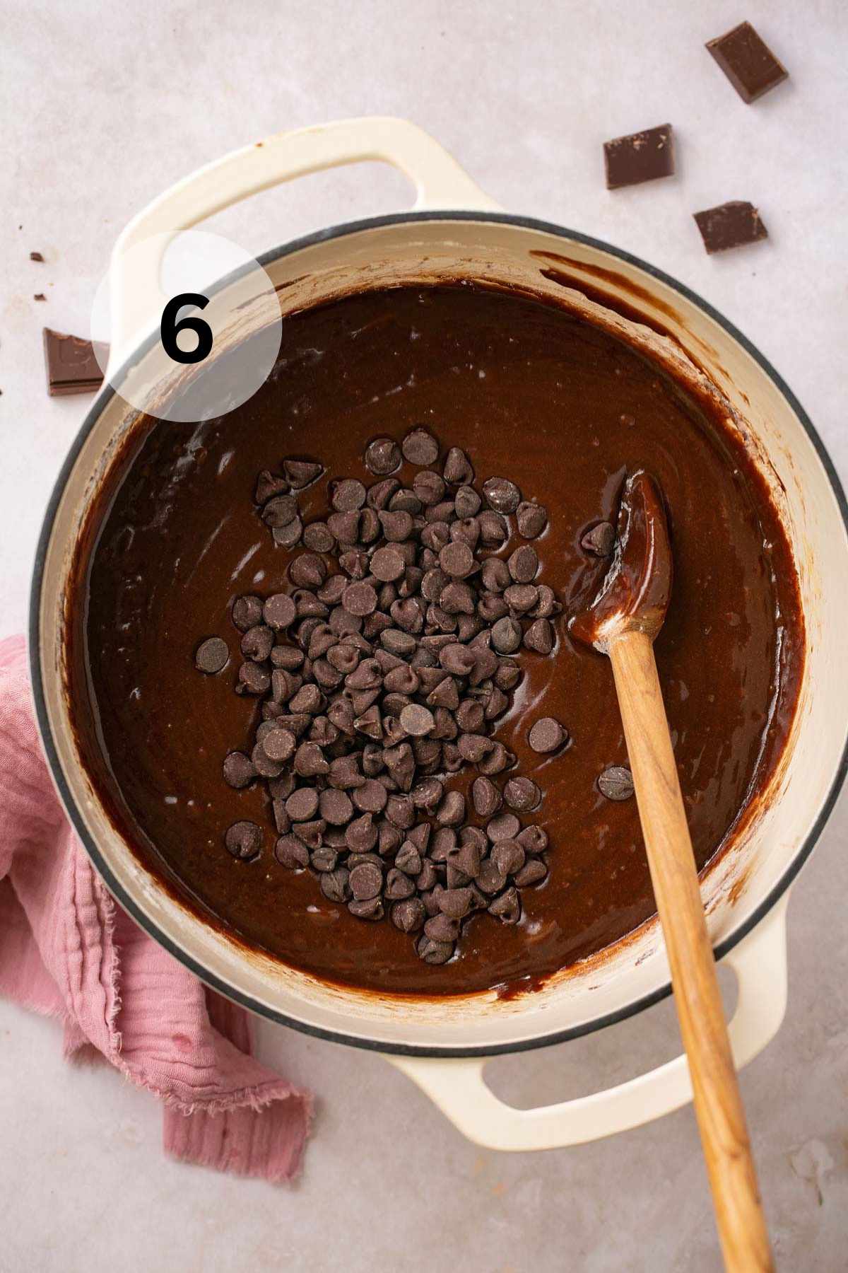 Using a wooden spoon to stir chocolate chips into brownie batter.