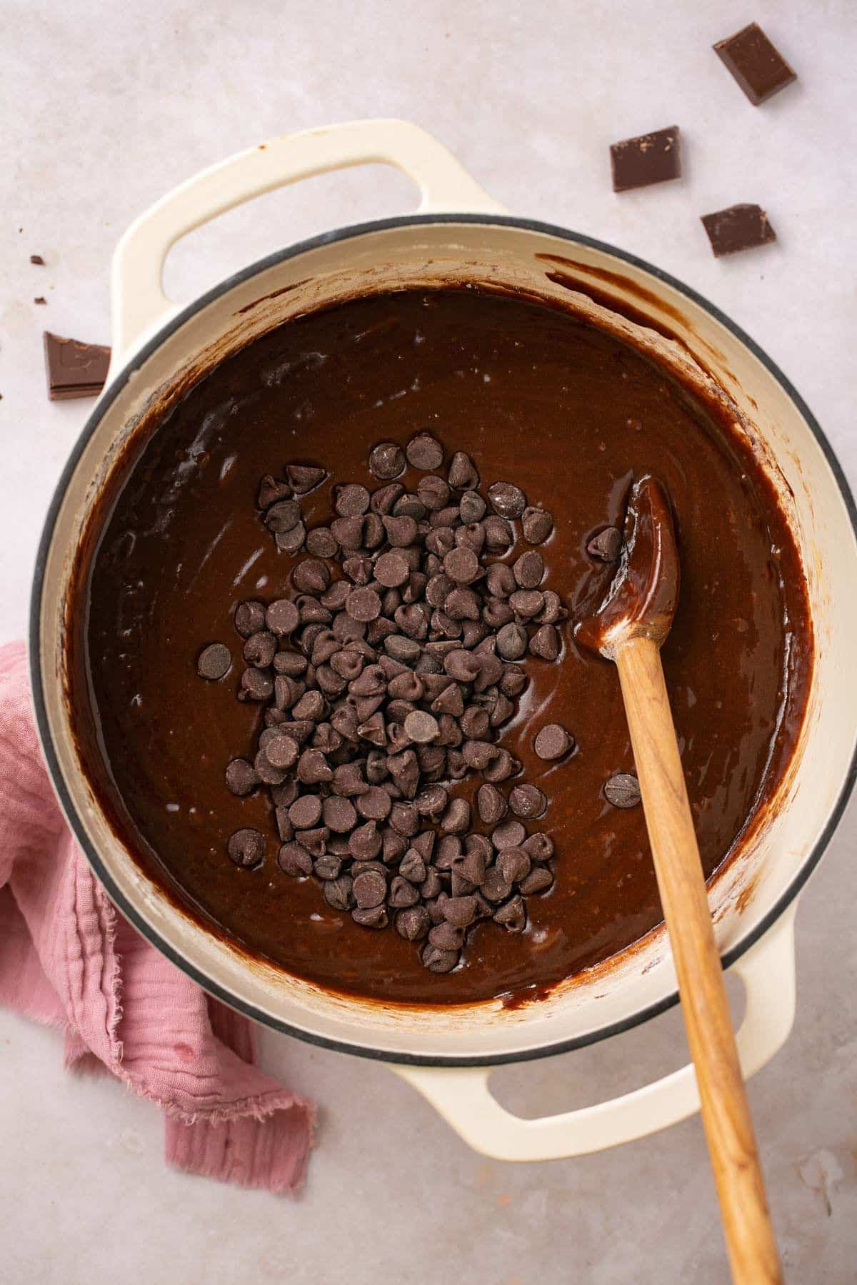 Using a wooden spoon to stir chocolate chips into brownie batter.