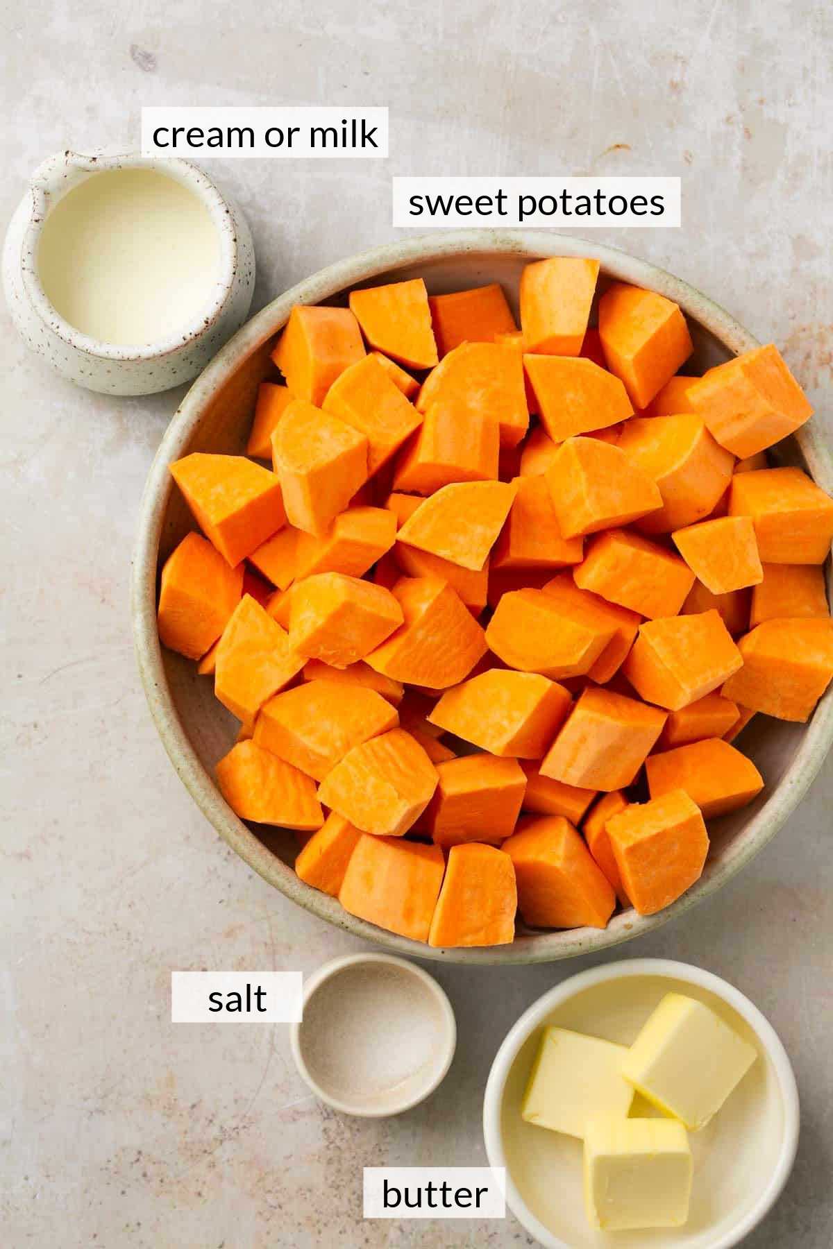 Cubed sweet potato in a bowl near cream and butter.