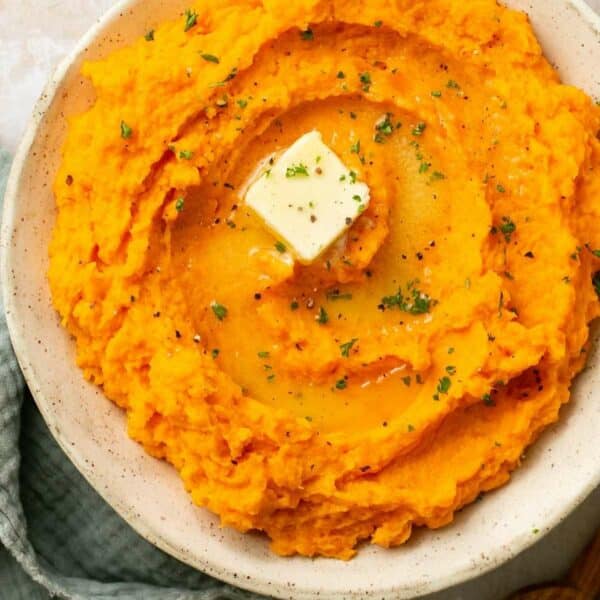 Creamy sweet potatoes topped with butter and garnished with chopped parsley.