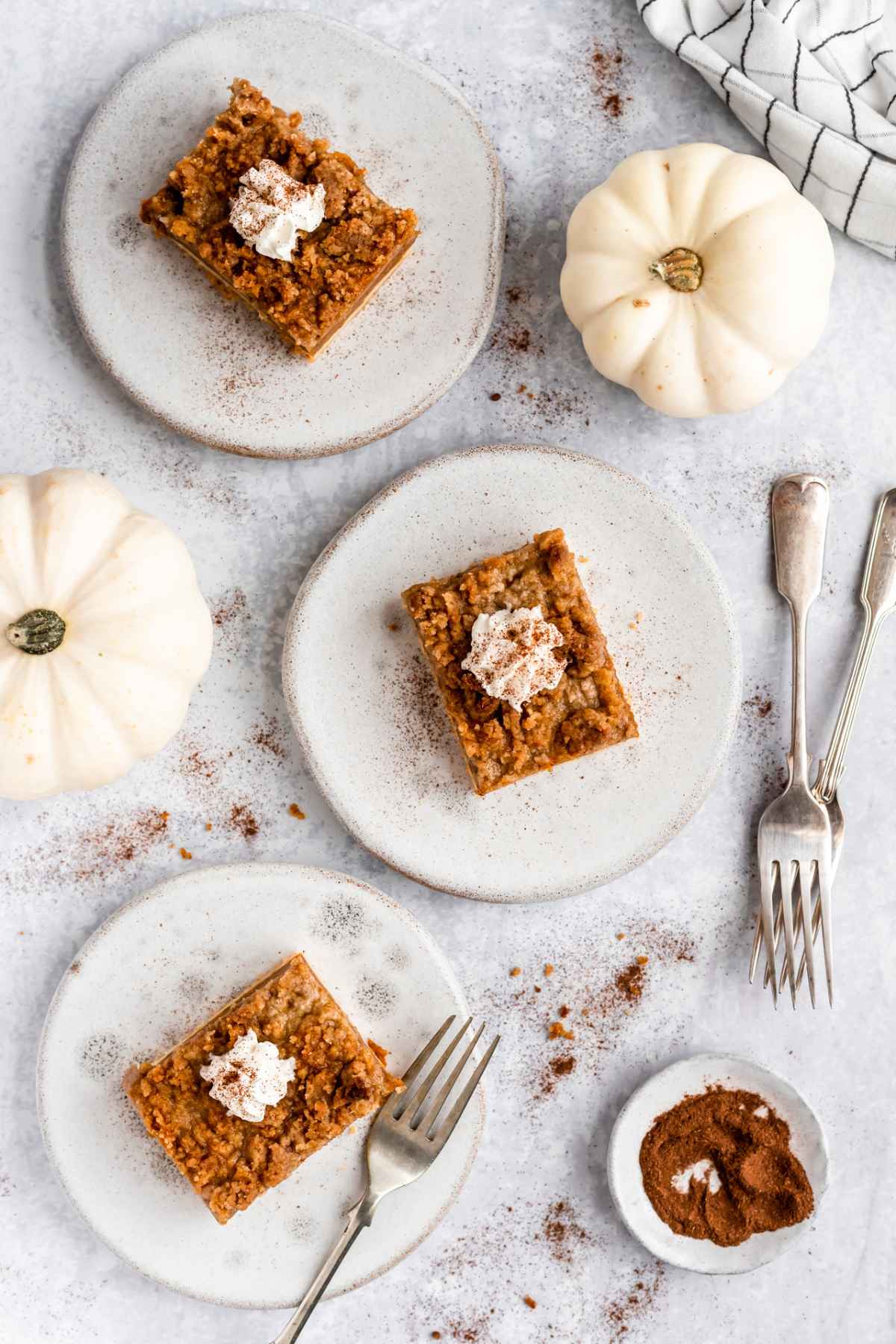 Pumpkin bars topped with whipped cream served on white plates. 
