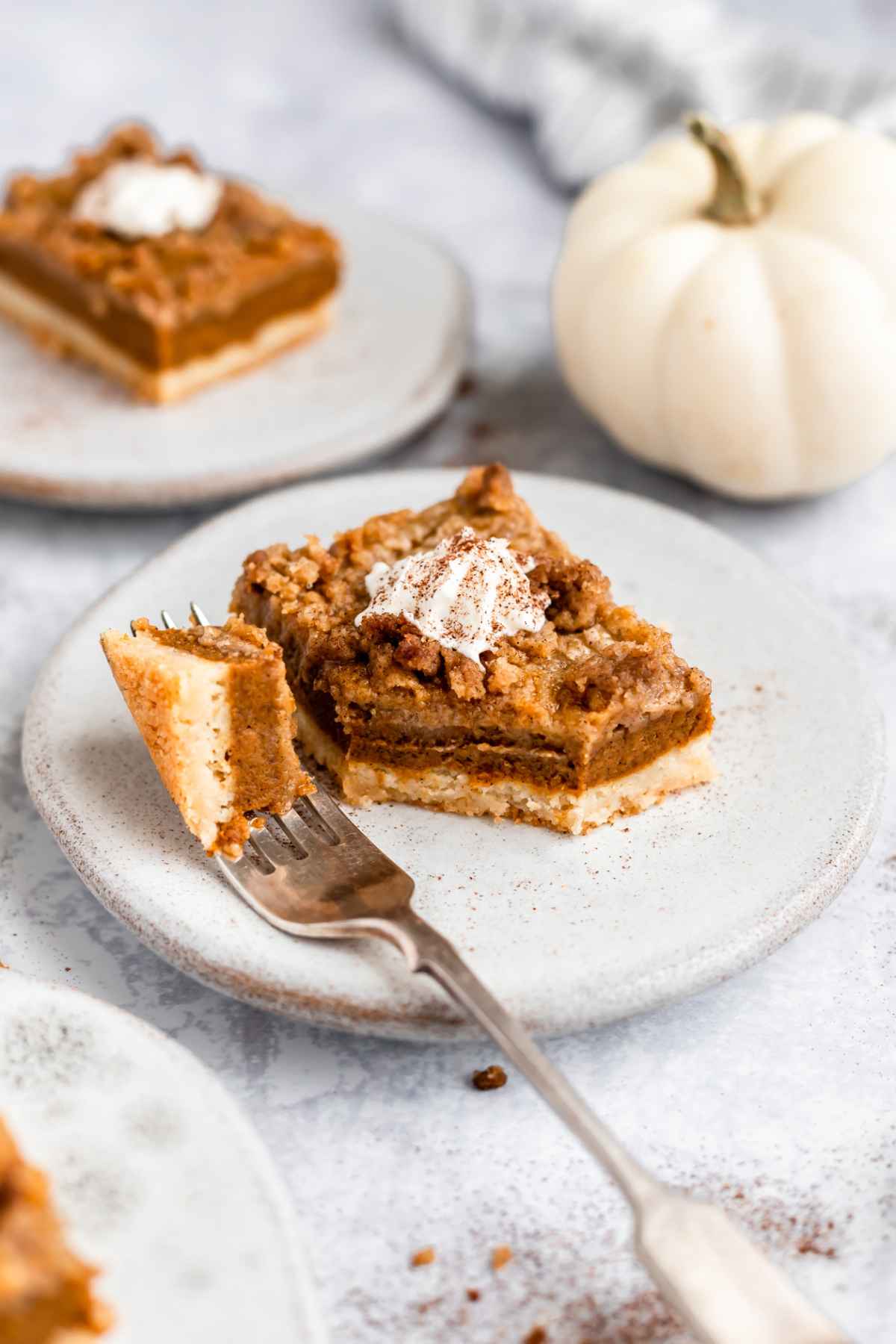 Pumpkin bars served on small white plates with whipped cream.