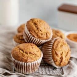 Stacked pumpkin muffins on a wire rack.
