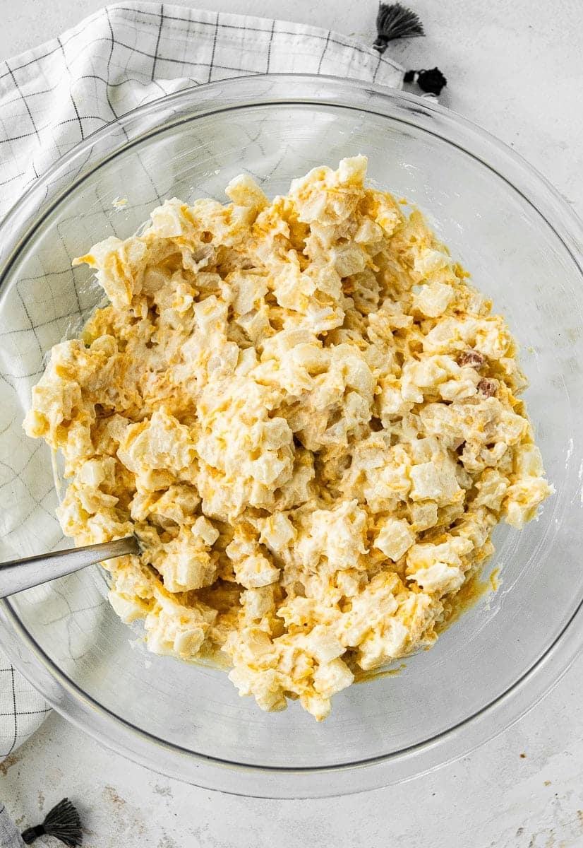 Mixing diced potatoes with sour cream, cheese and canned soup.