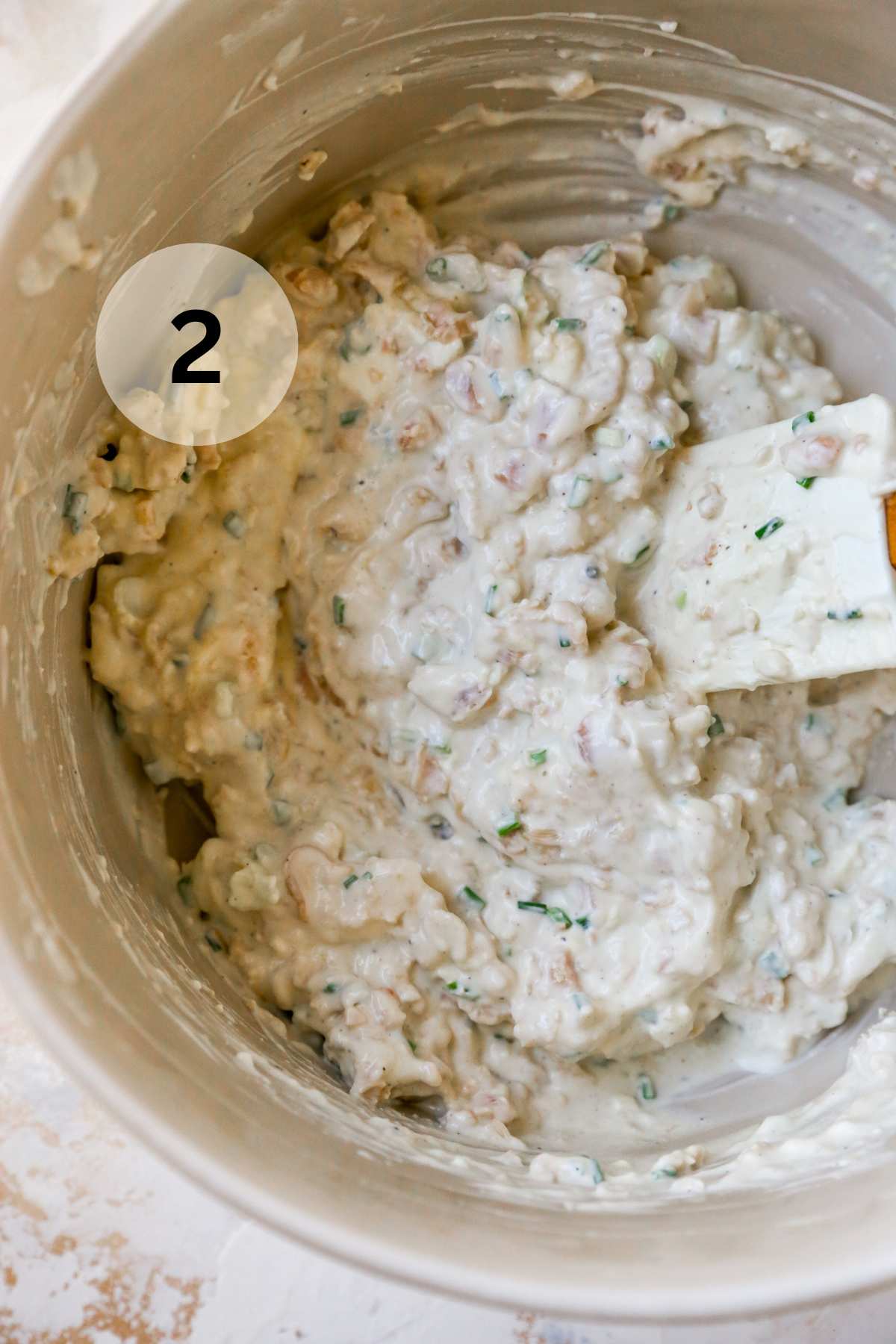 Using a spatula to stir clam dip in a bowl.