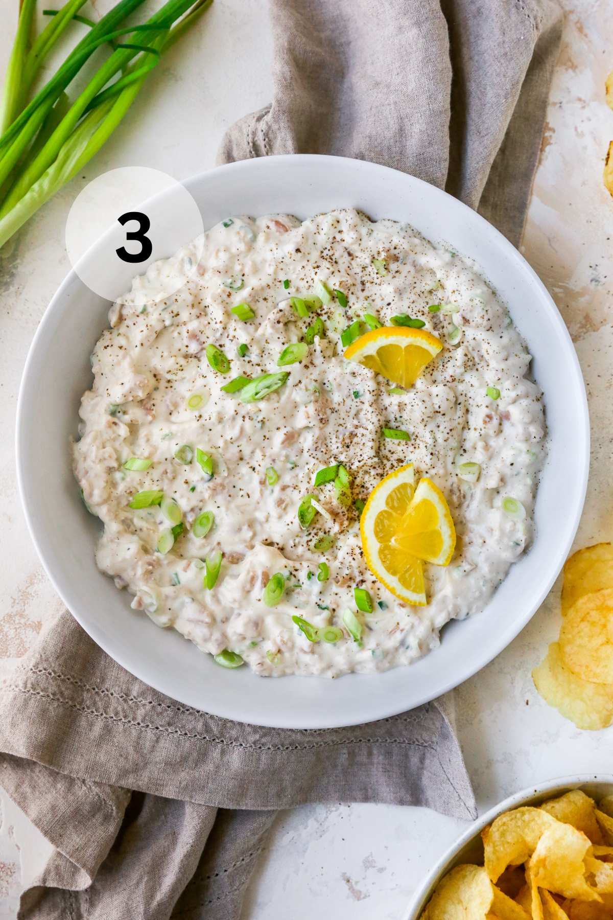 Clam dip served with green onions and topped with lemon slices.