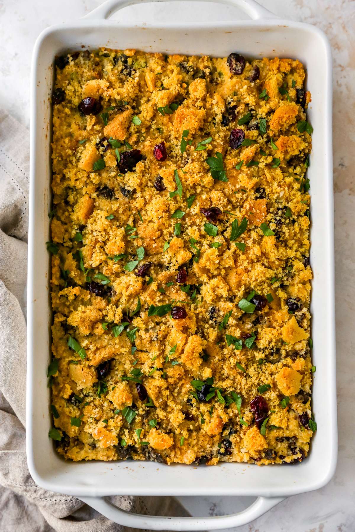 Baked cornbread stuffing in large white casserole dish.
