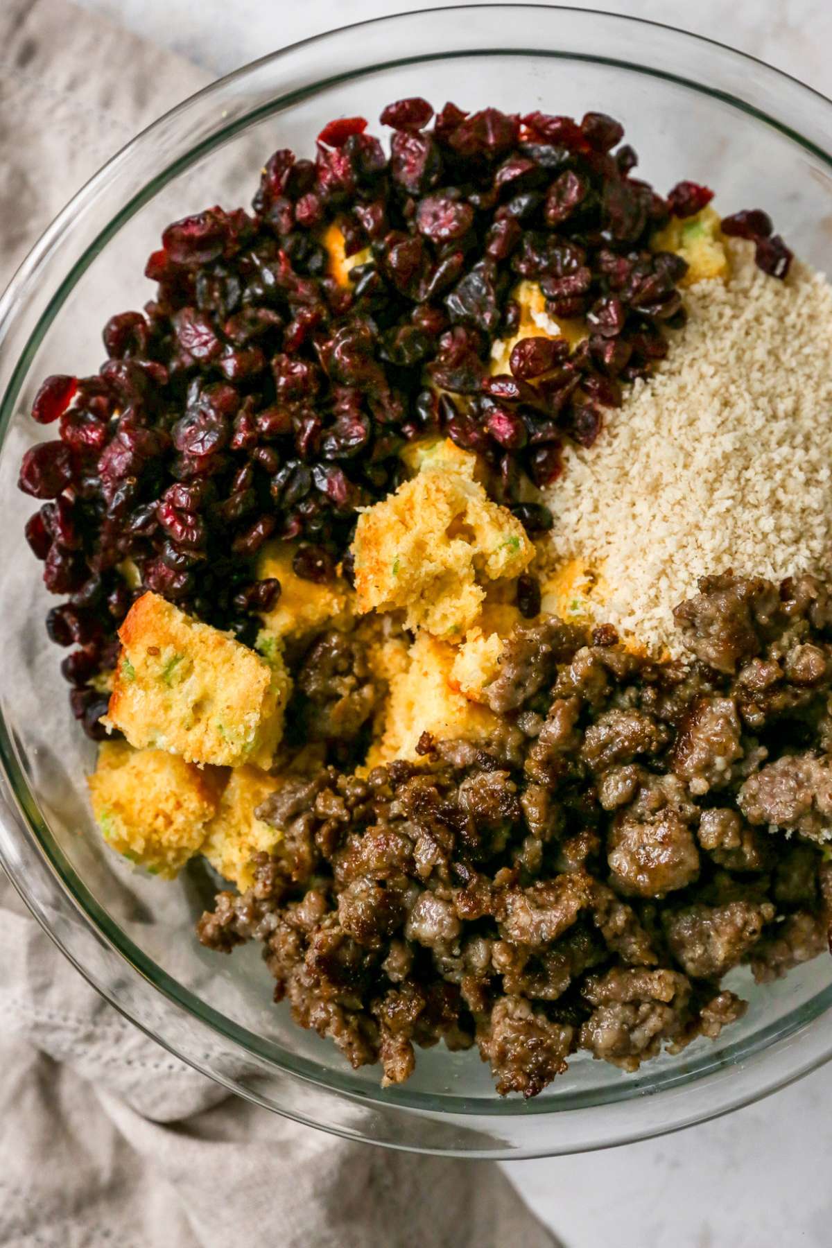 Cornbread, cranberries, sausage and breadcrumbs add to a bowl.