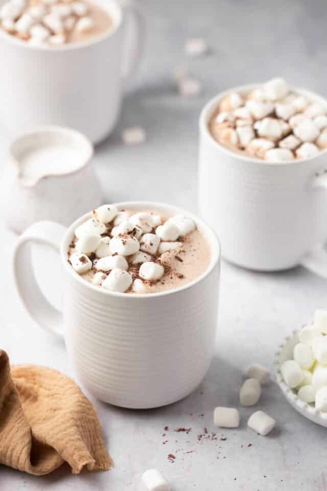 White mugs filled with hot cocoa and marshmallows.