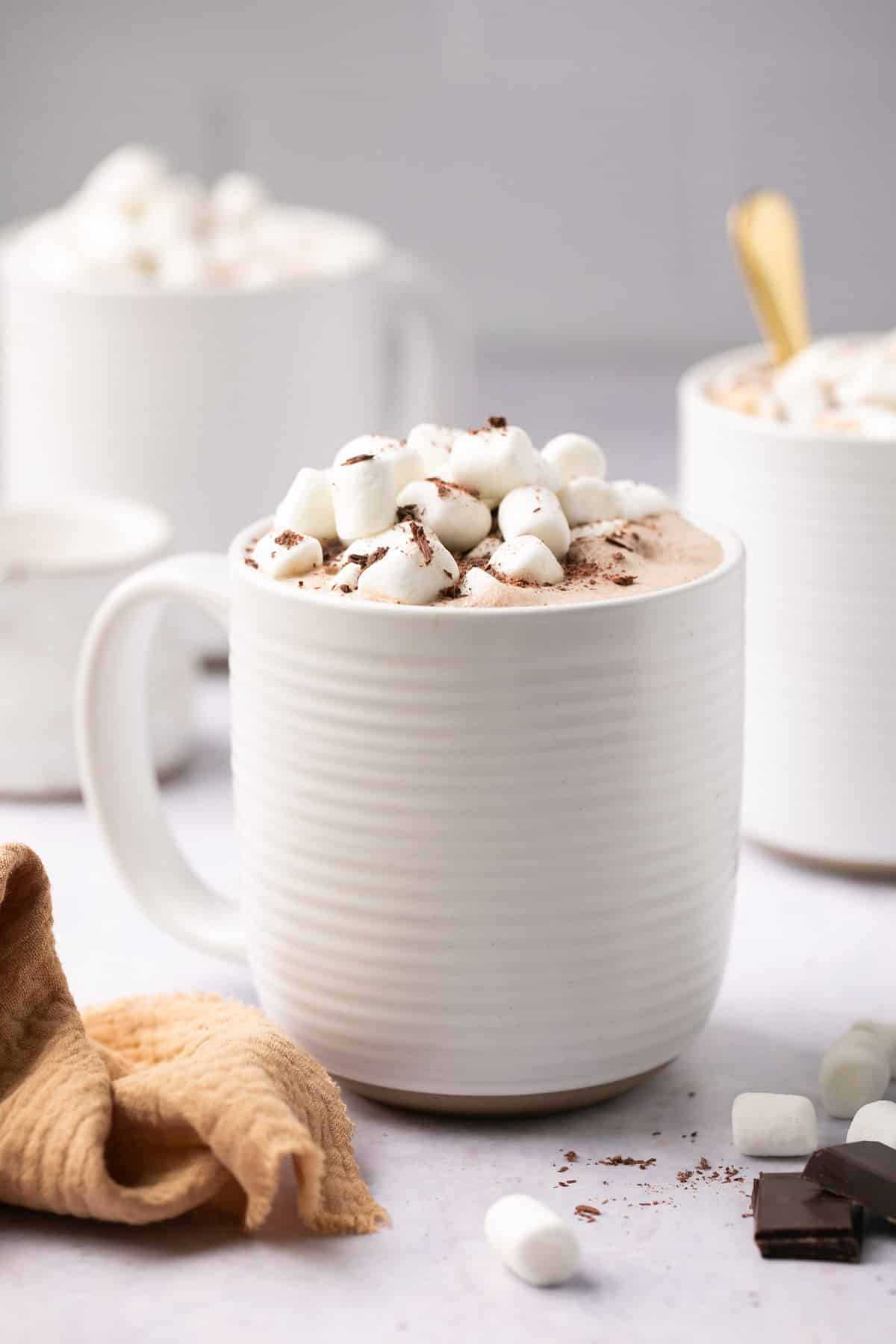 Hot chocolate served in white mugs with marshmallows.