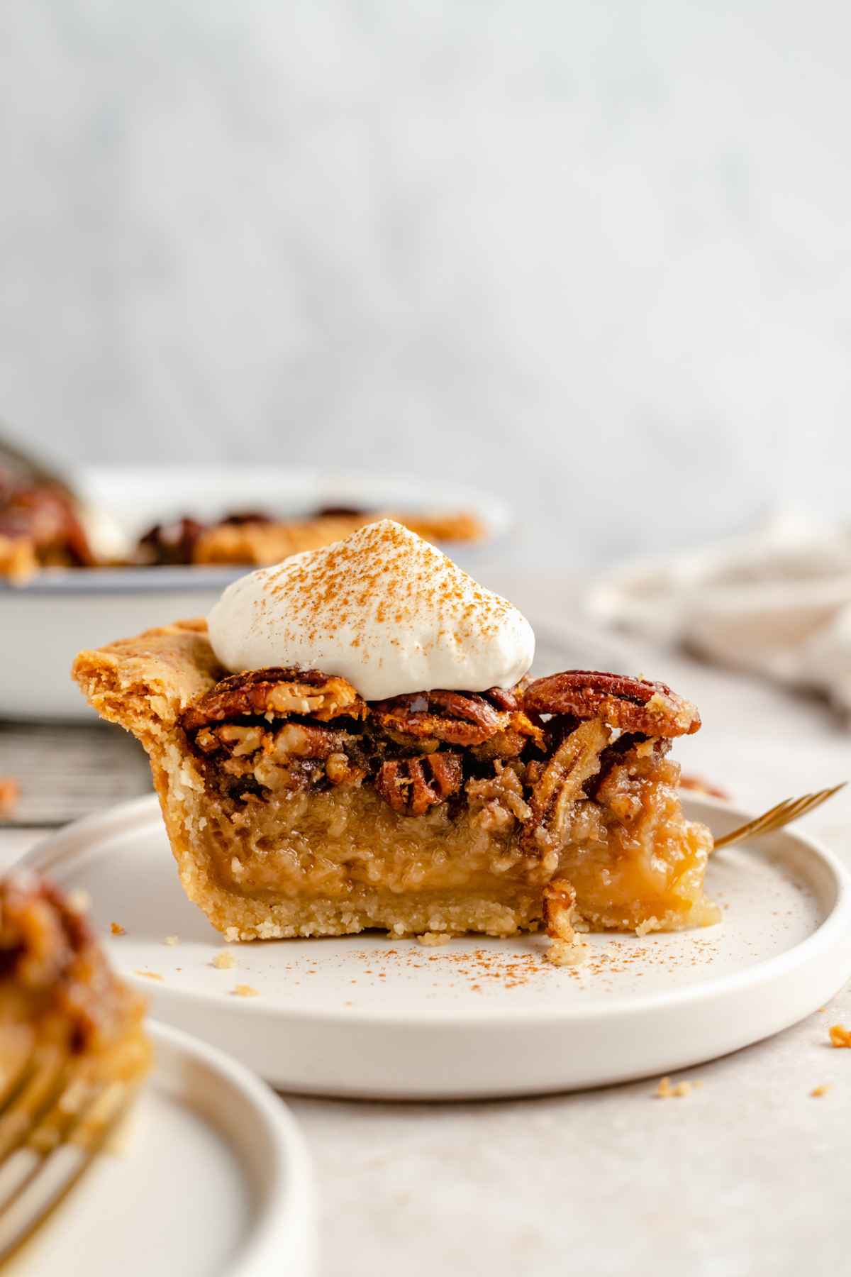 Side view of a slice of pecan pie with a dollop of whipped cream.