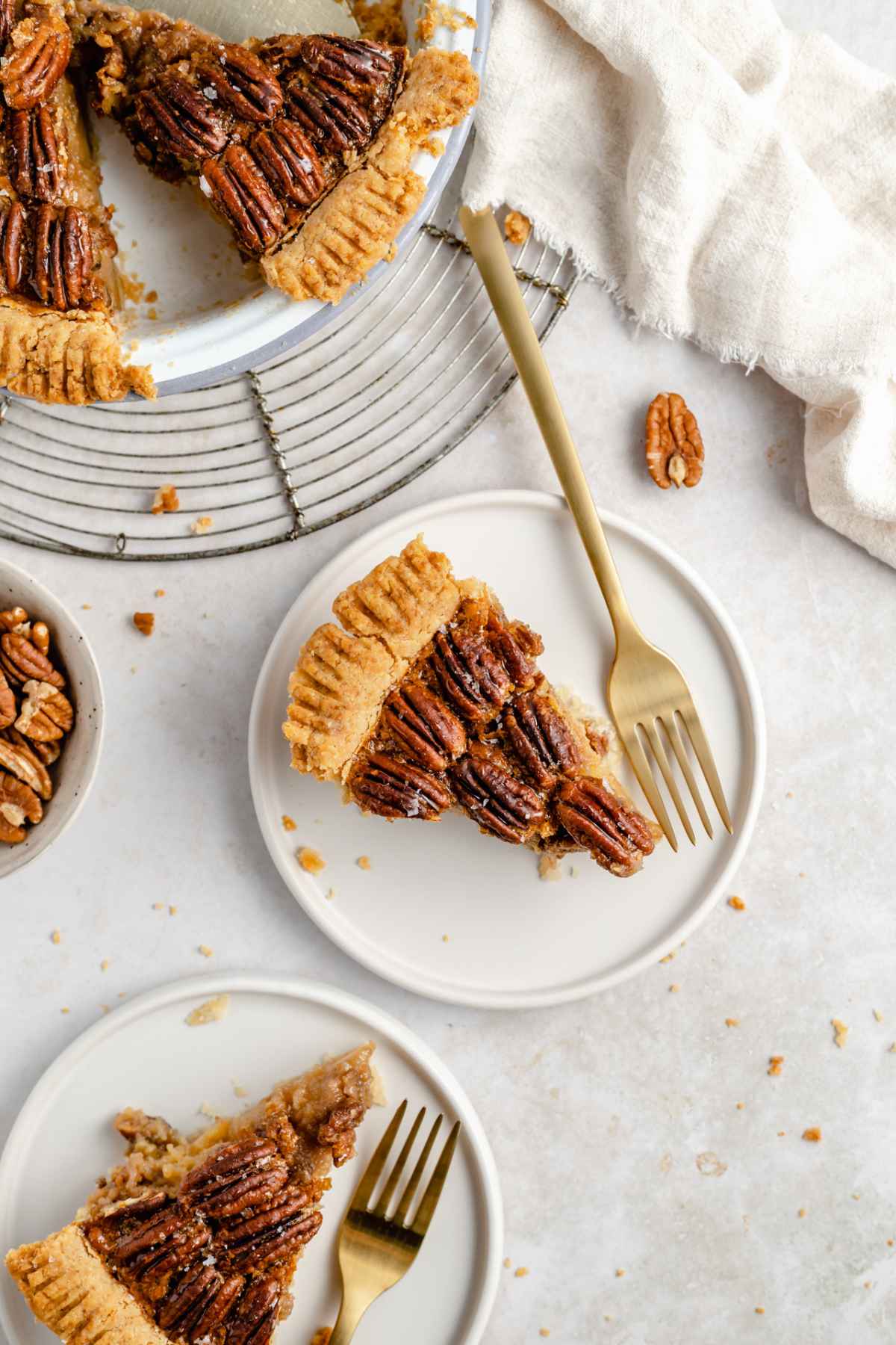 Slices of pie topped with pecans on white plates.