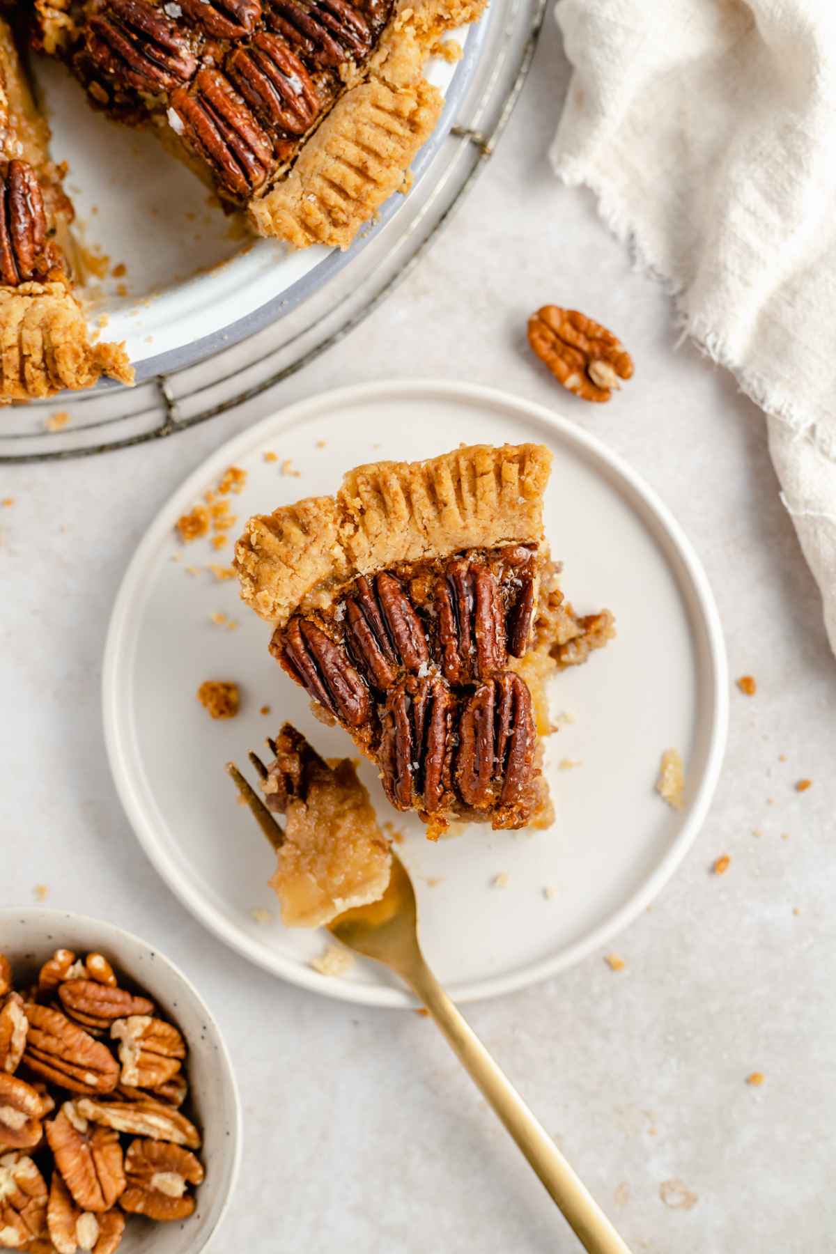 Slice of pecan pie on a white plate with a fork.