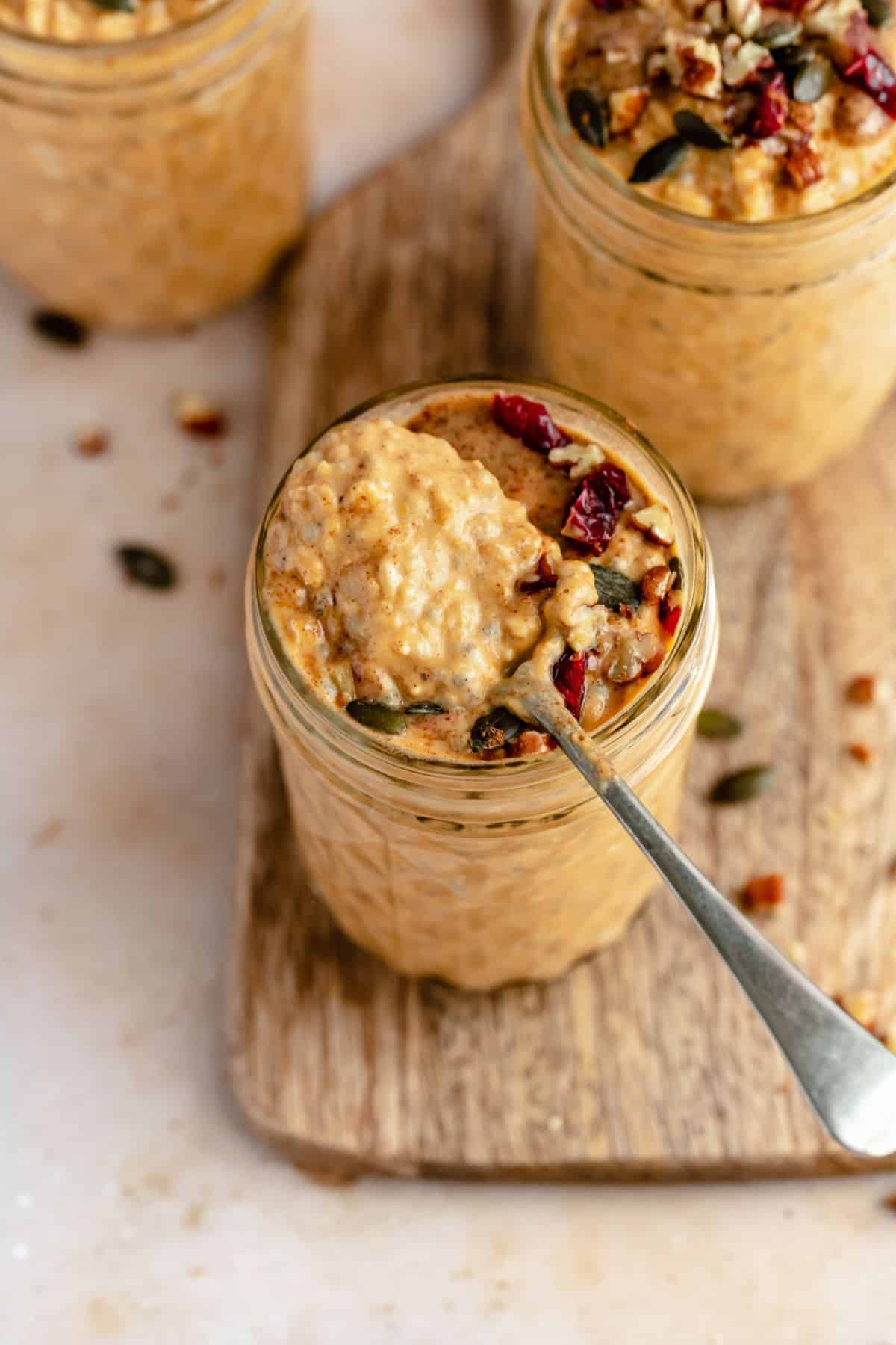 Overnight oats made with pumpkin topped with pumpkin seeds and cranberries.