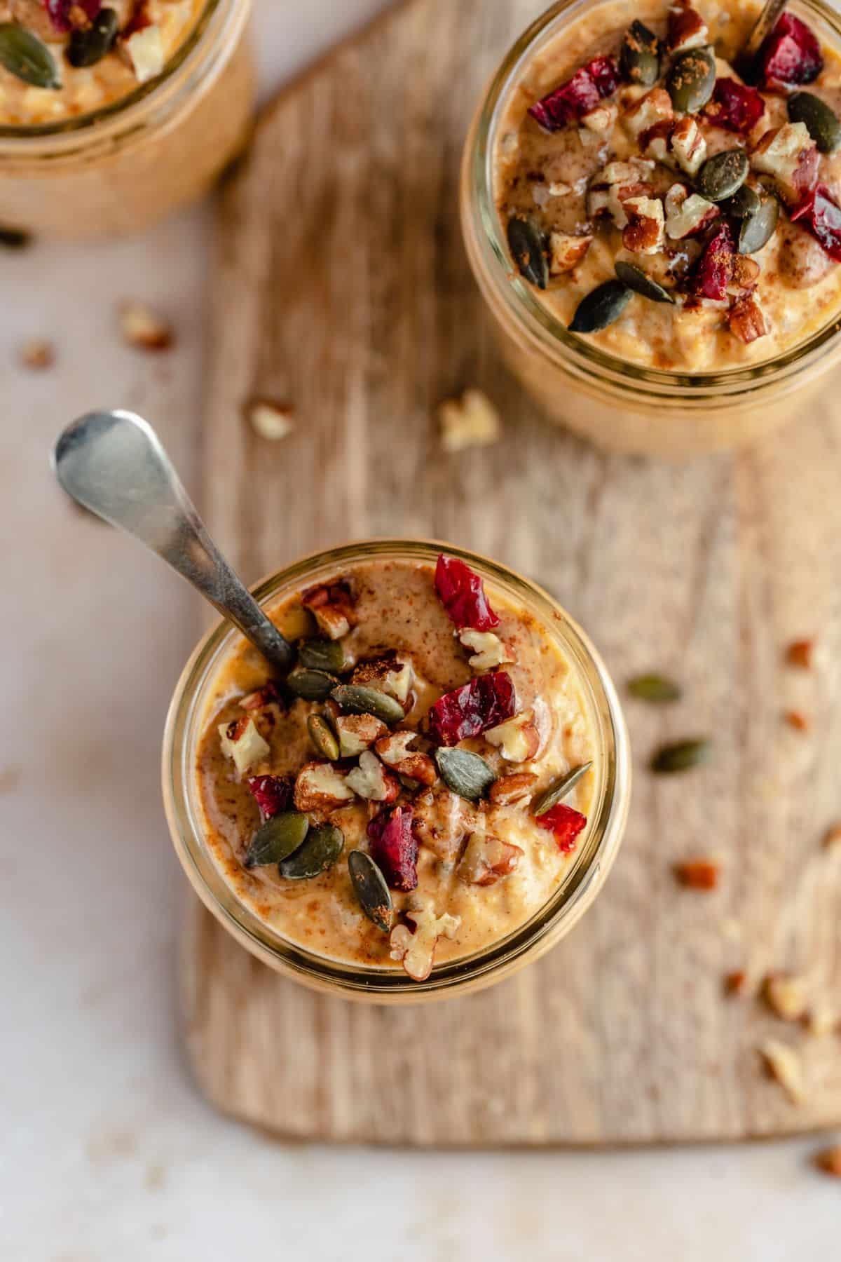 Oatmeal topped with pumpkin seeds and cranberries in a small jar.