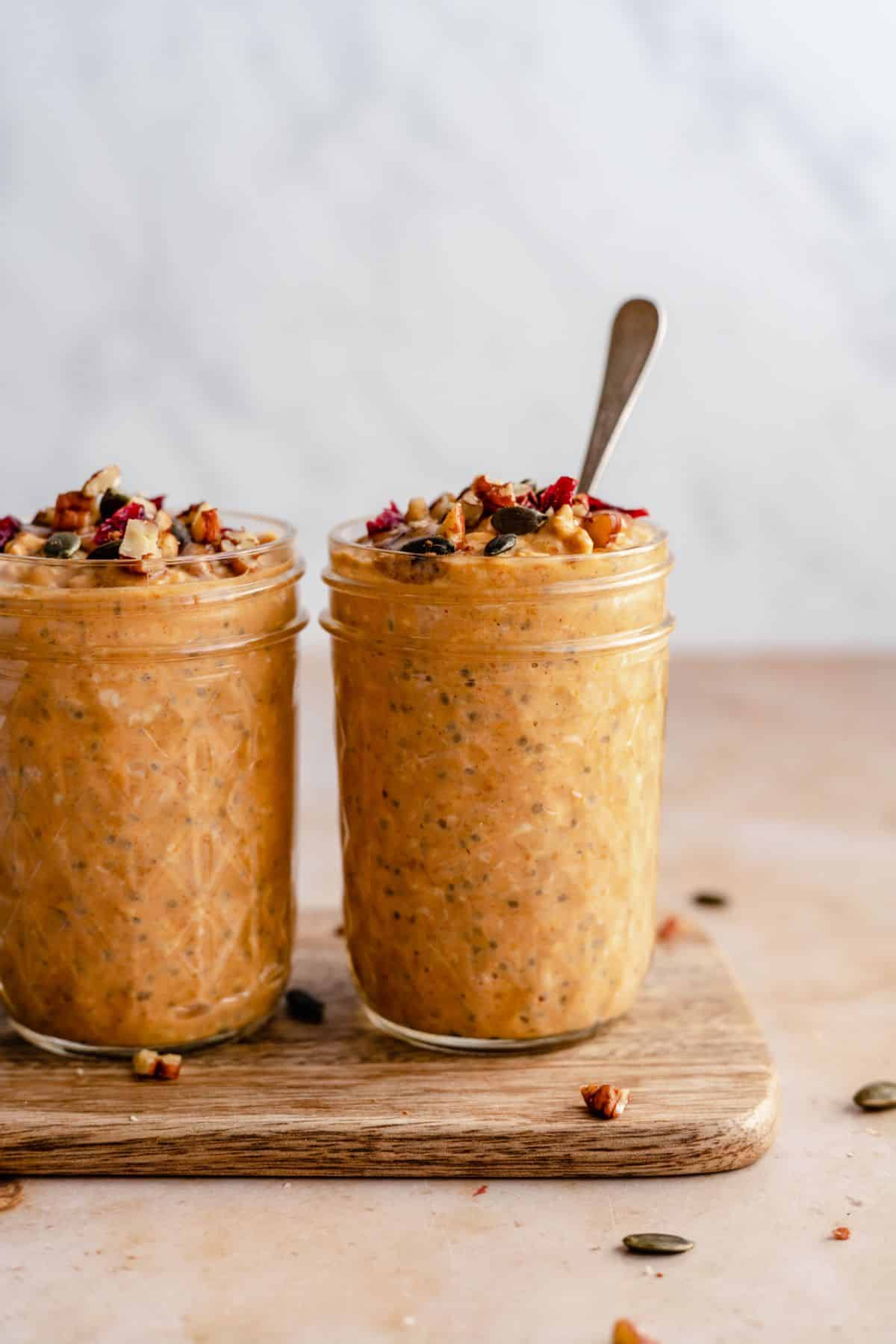 Pumpkin overnight oats in jars with a spoon.
