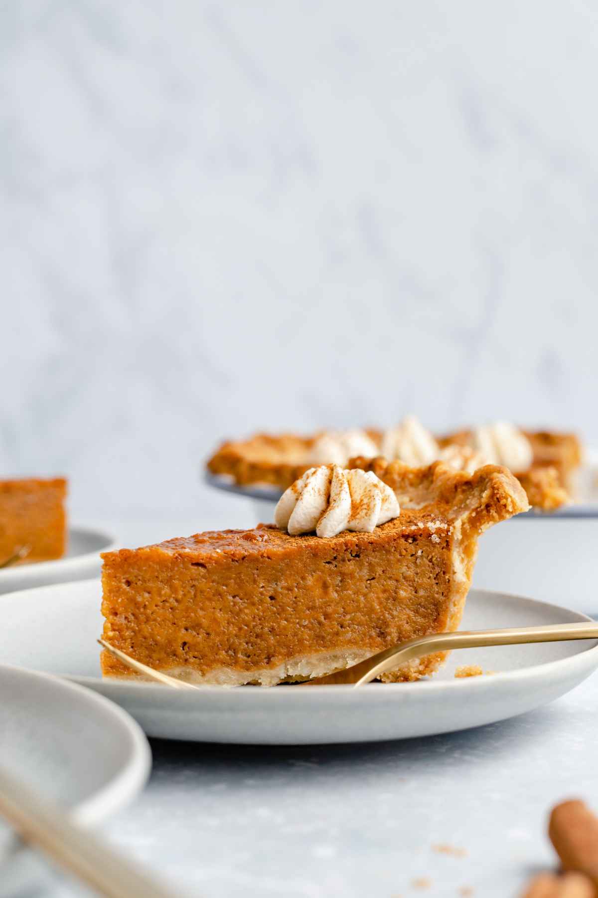 Slice of pie topped with whipped cream on a white plate.