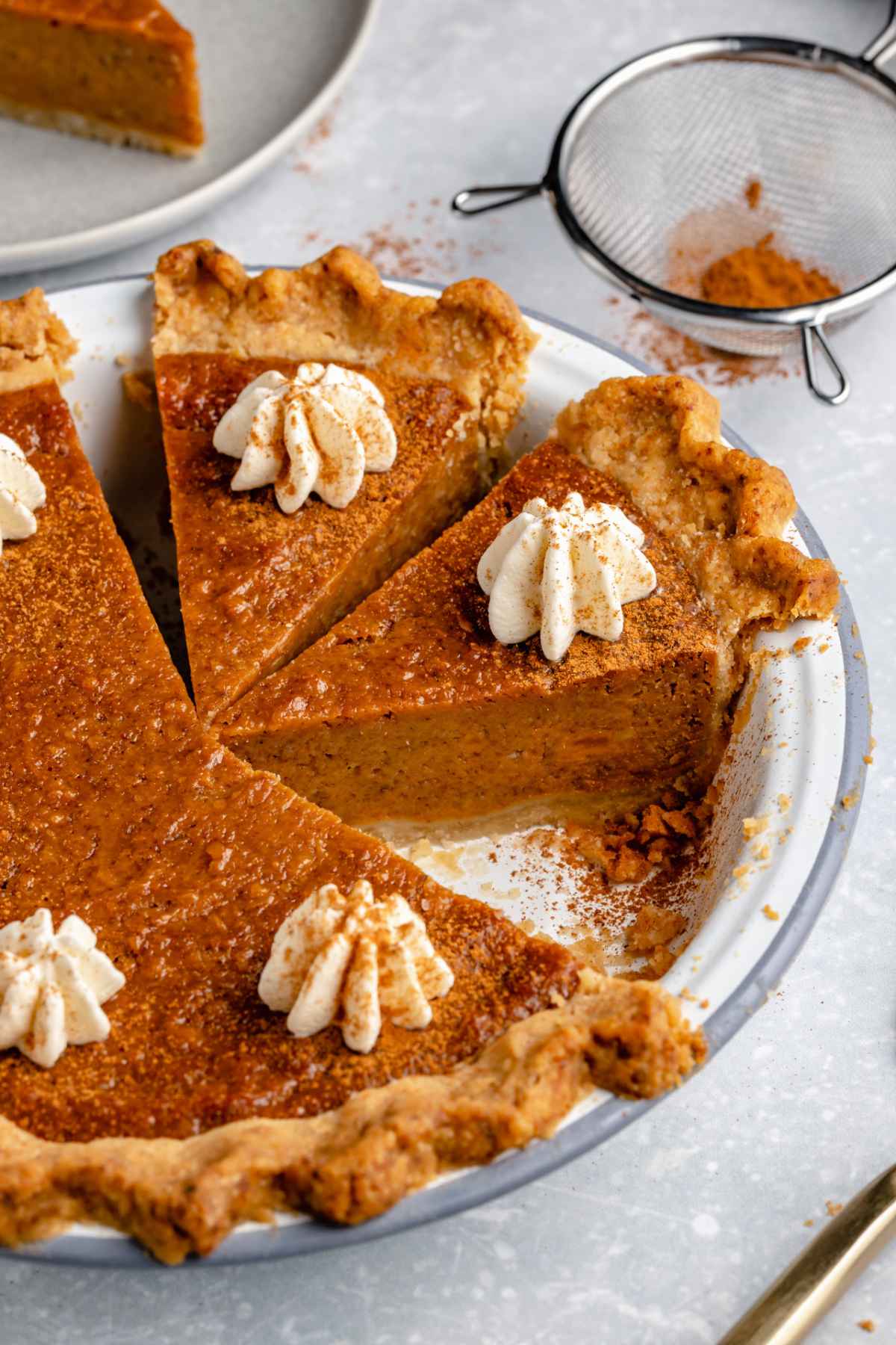 Slices of sweet potato pie topped with whipped cream in a pie plate.