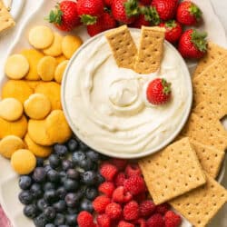 Cream cheese fruit dip on a platter with berries and cookies.