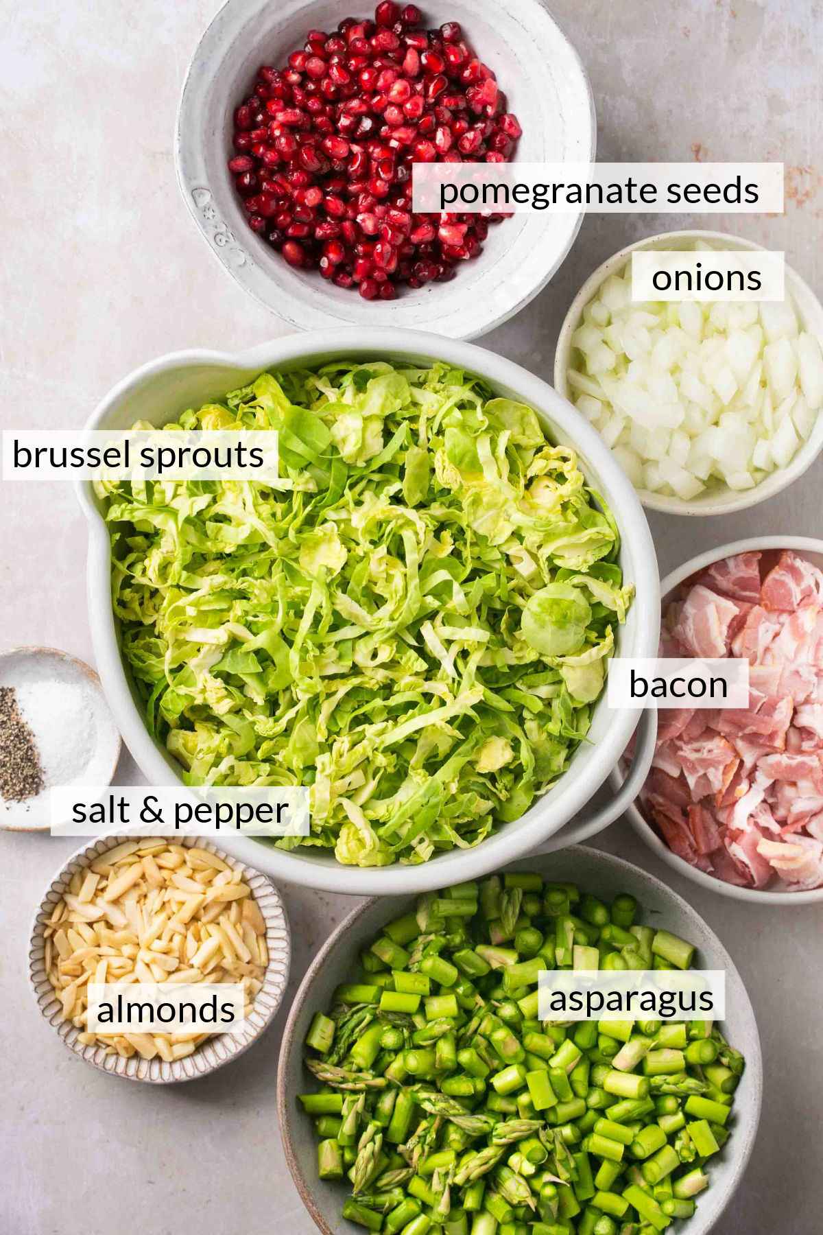 Shaved brussels sprouts and other ingredients in small bowls.