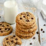 Chocolate chip oatmeal cookies stacked on parchment paper.