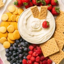 Cream cheese fruit dip on a platter with berries and cookies.
