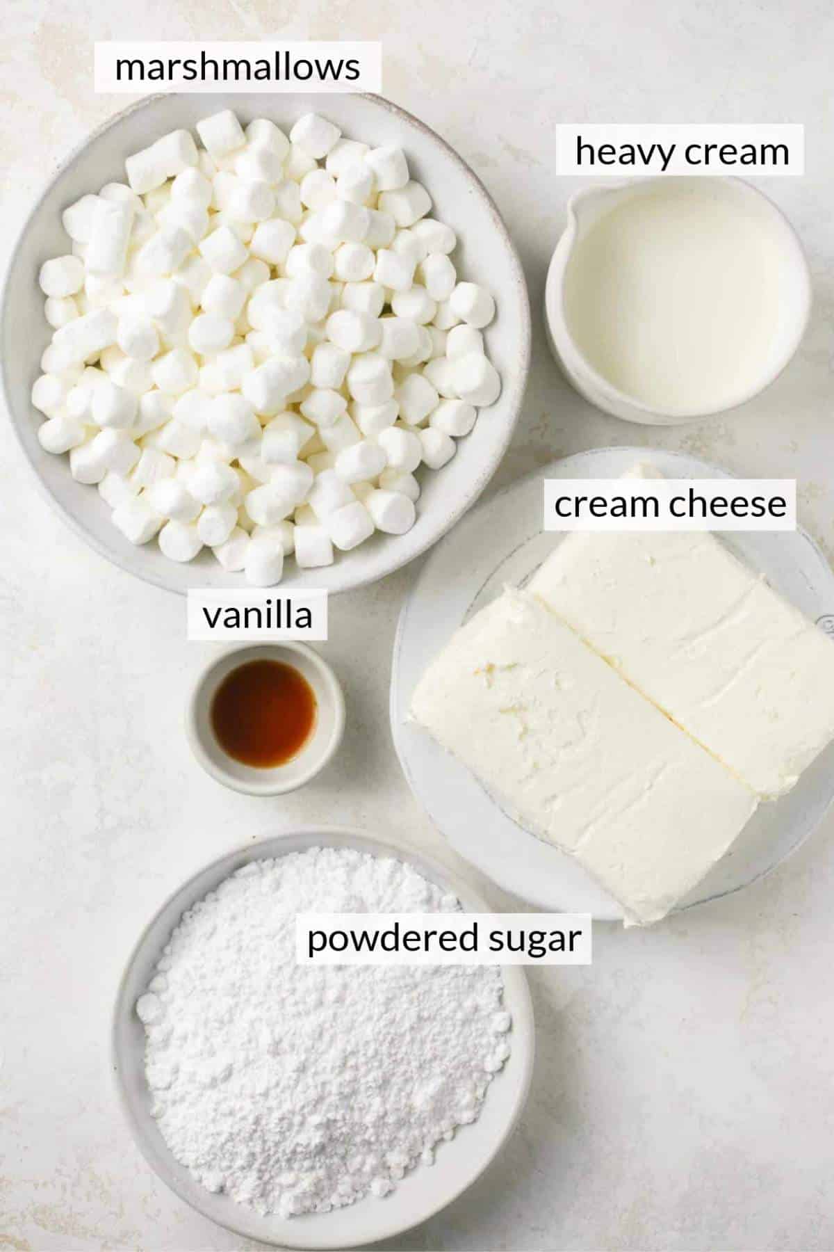 Marshmallows, vanilla, powdered sugar and cream cheese in small white bowls.