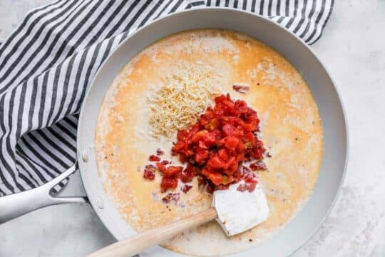 Combining tomatoes with cream in a skillet.