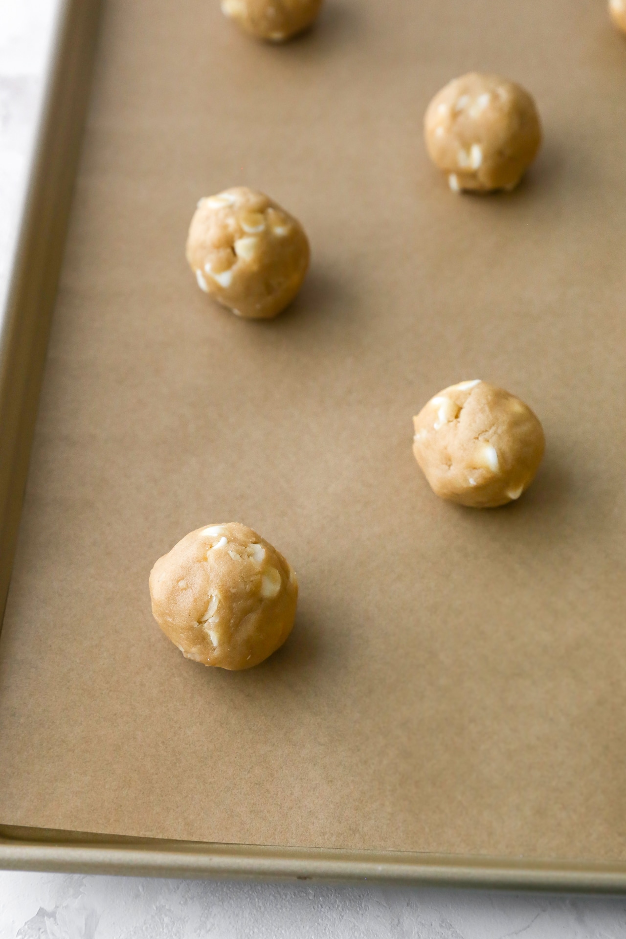 Cookie dough formed into balls on a cookie sheet.