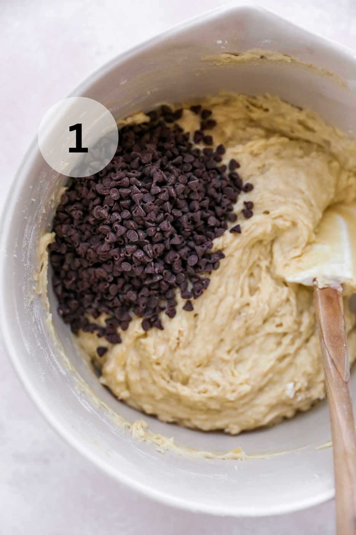 Adding chocolate chips to muffin batter in bowl.
