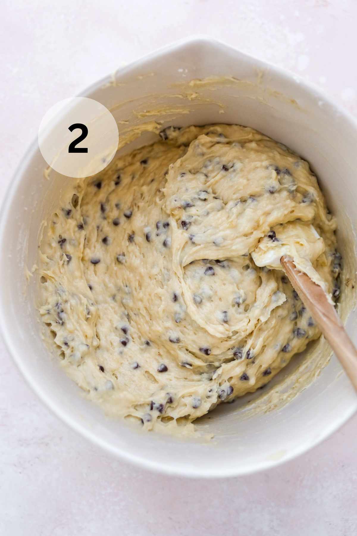Chocolate chip batter in a large white bowl with a spatula.