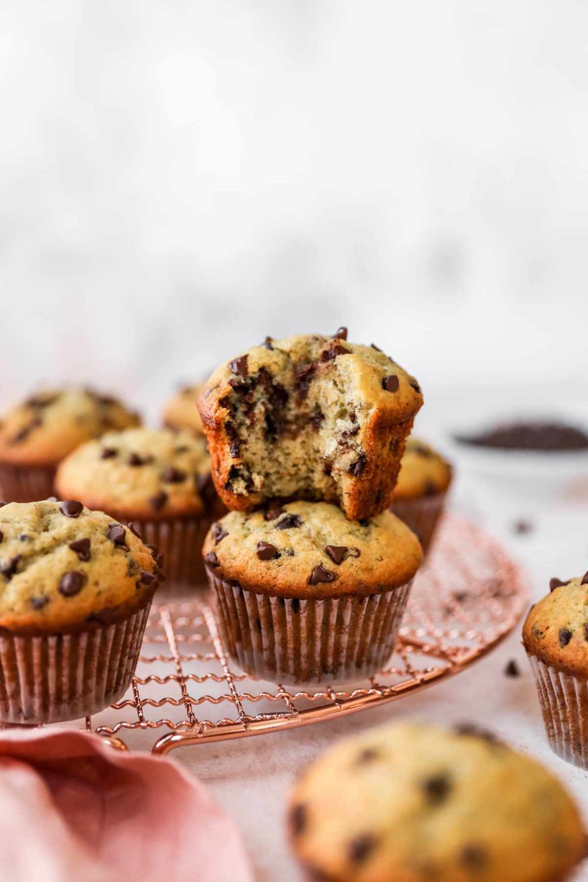 One chocolate chip muffin with a bite taken out stacked on another muffin.