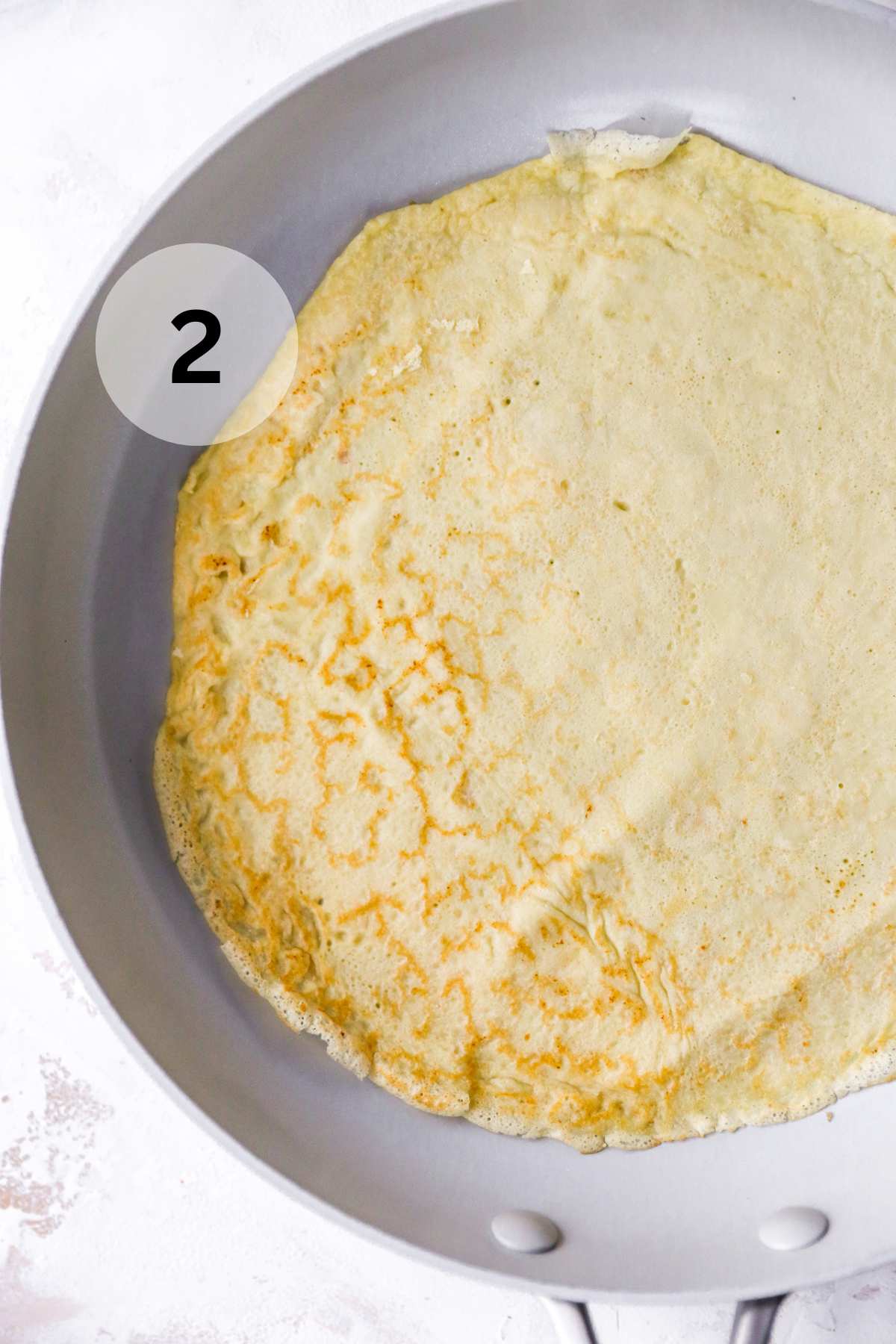 Crepe cooking in a large skillet.