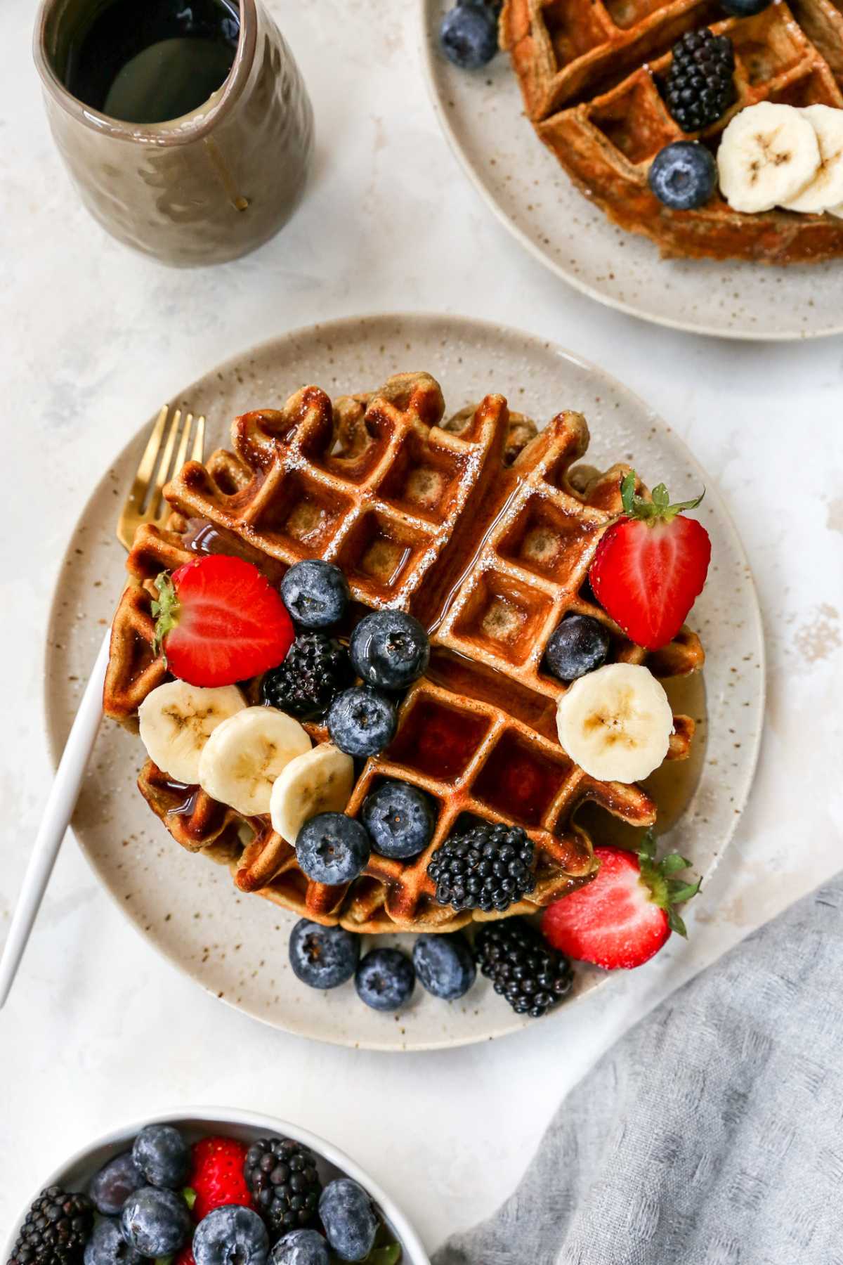 Protein waffle topped with berries and maple syrup on a plate.