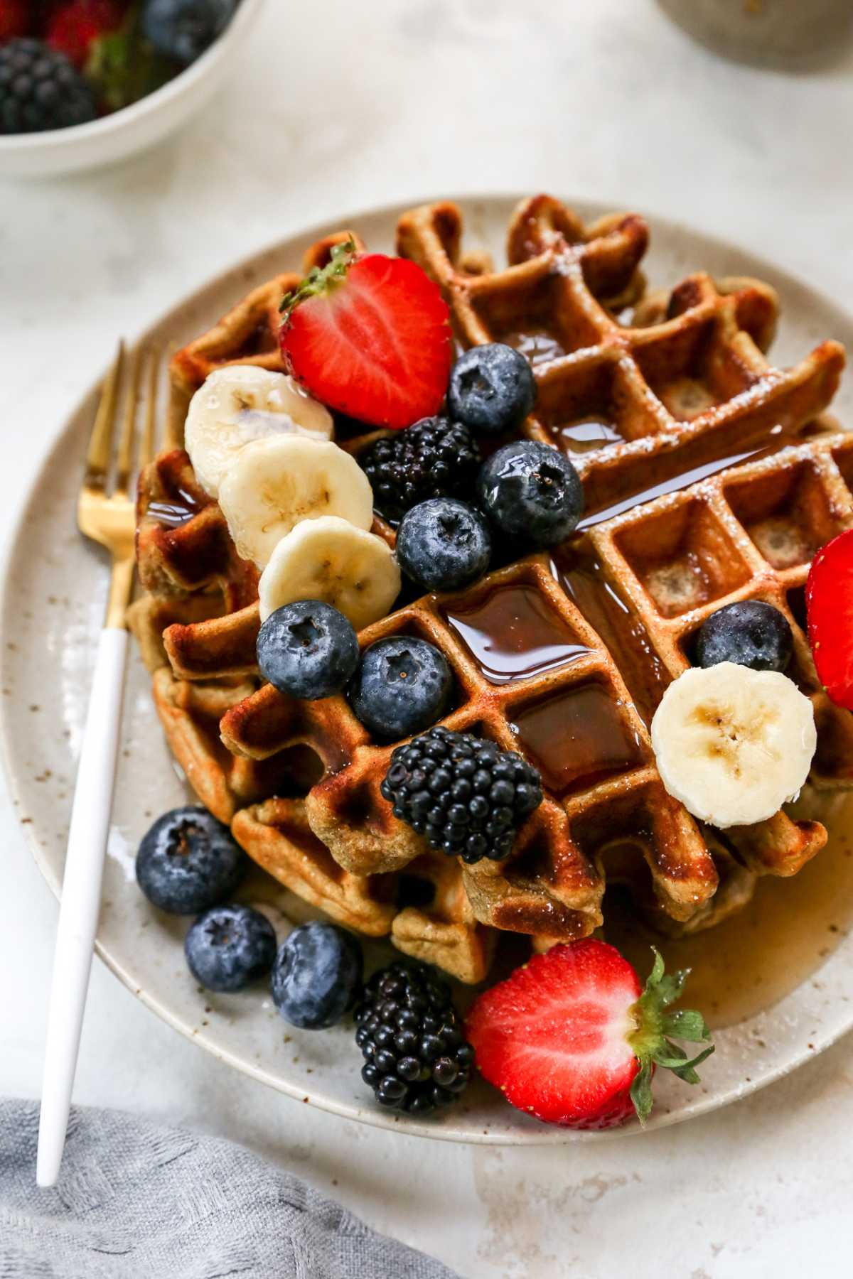 Waffle topped with maple syrup, berries and sliced banana.