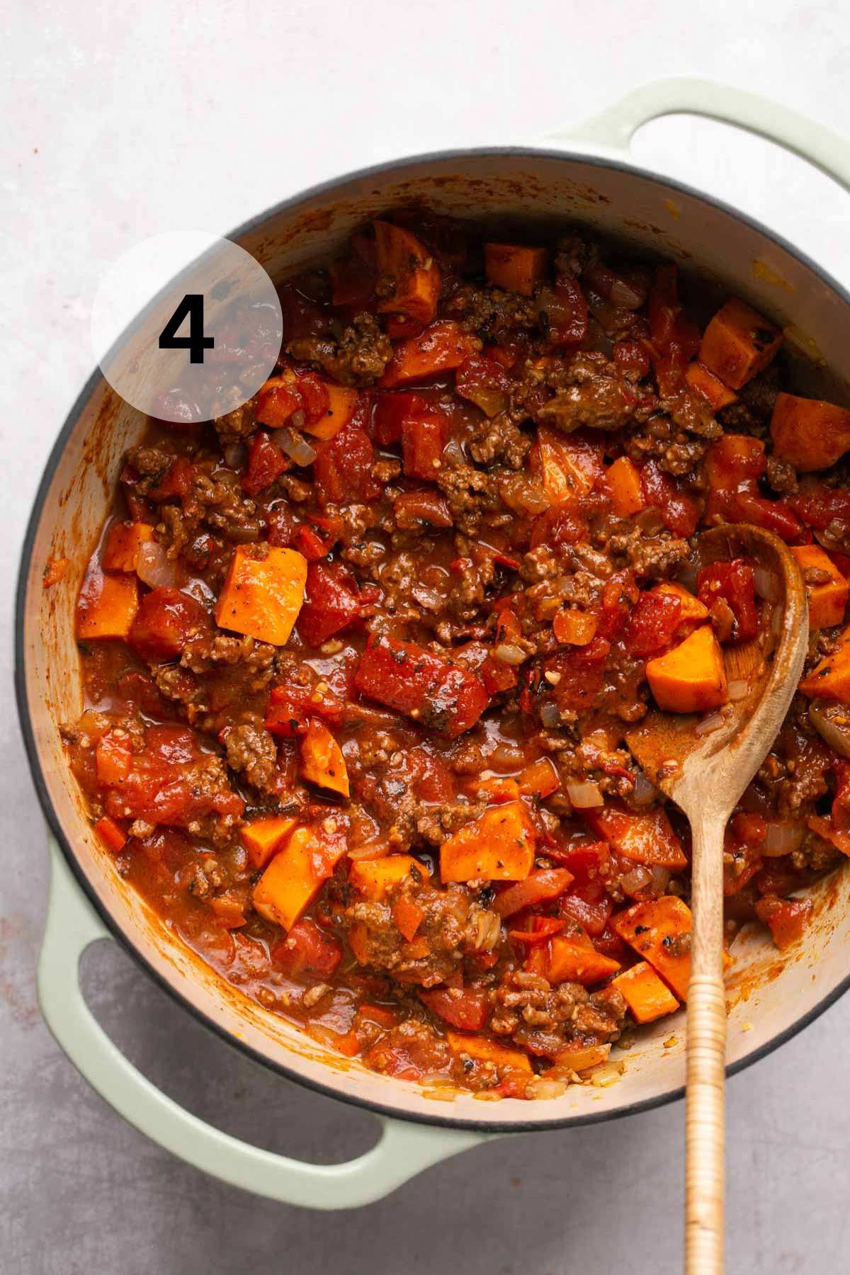 Stirring tomatoes and tomato paste into pot of chili.